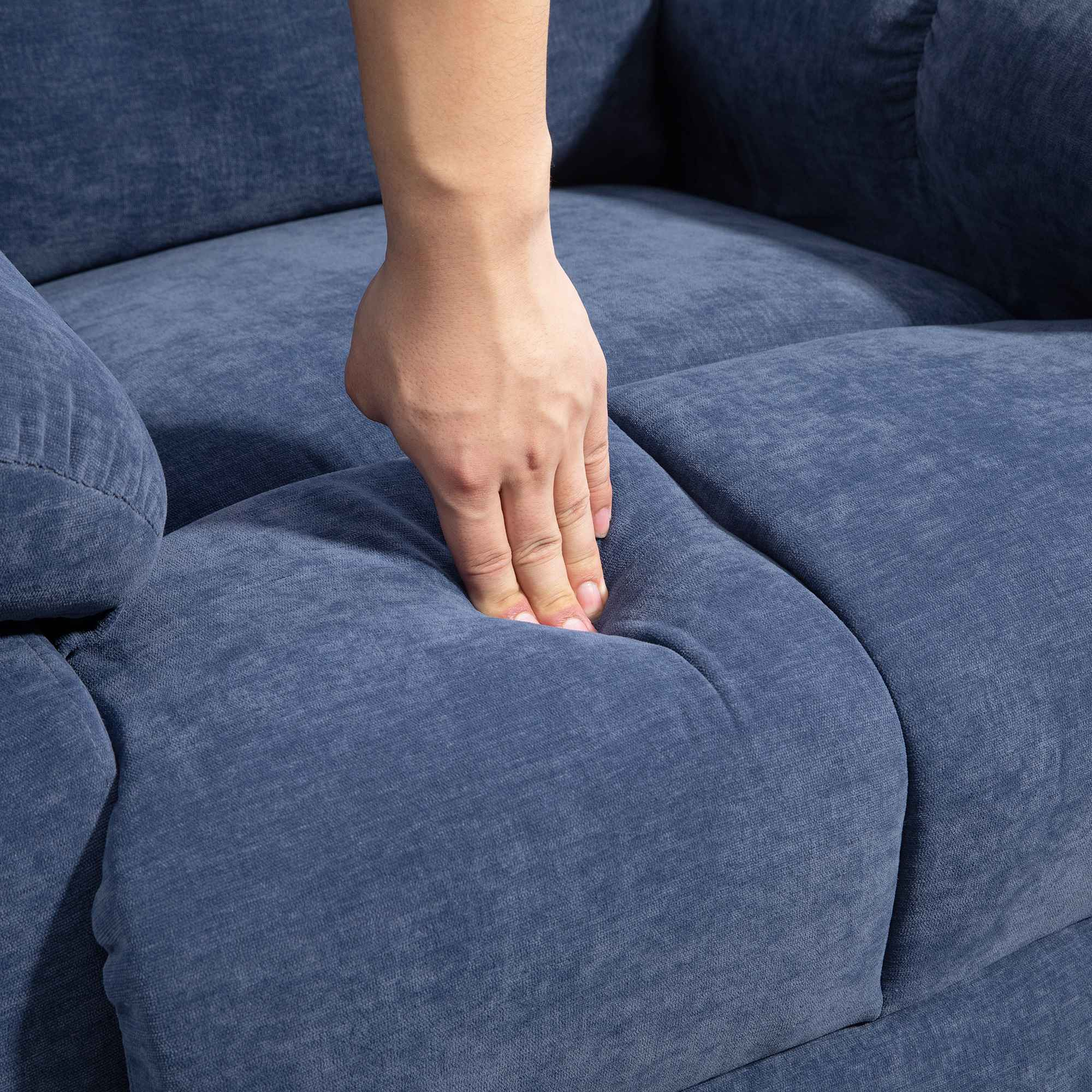 Eine Hand drückt auf ein blau gepolstertes Sofakissen. Das Kissen verformt sich, wo die Hand es berührt.