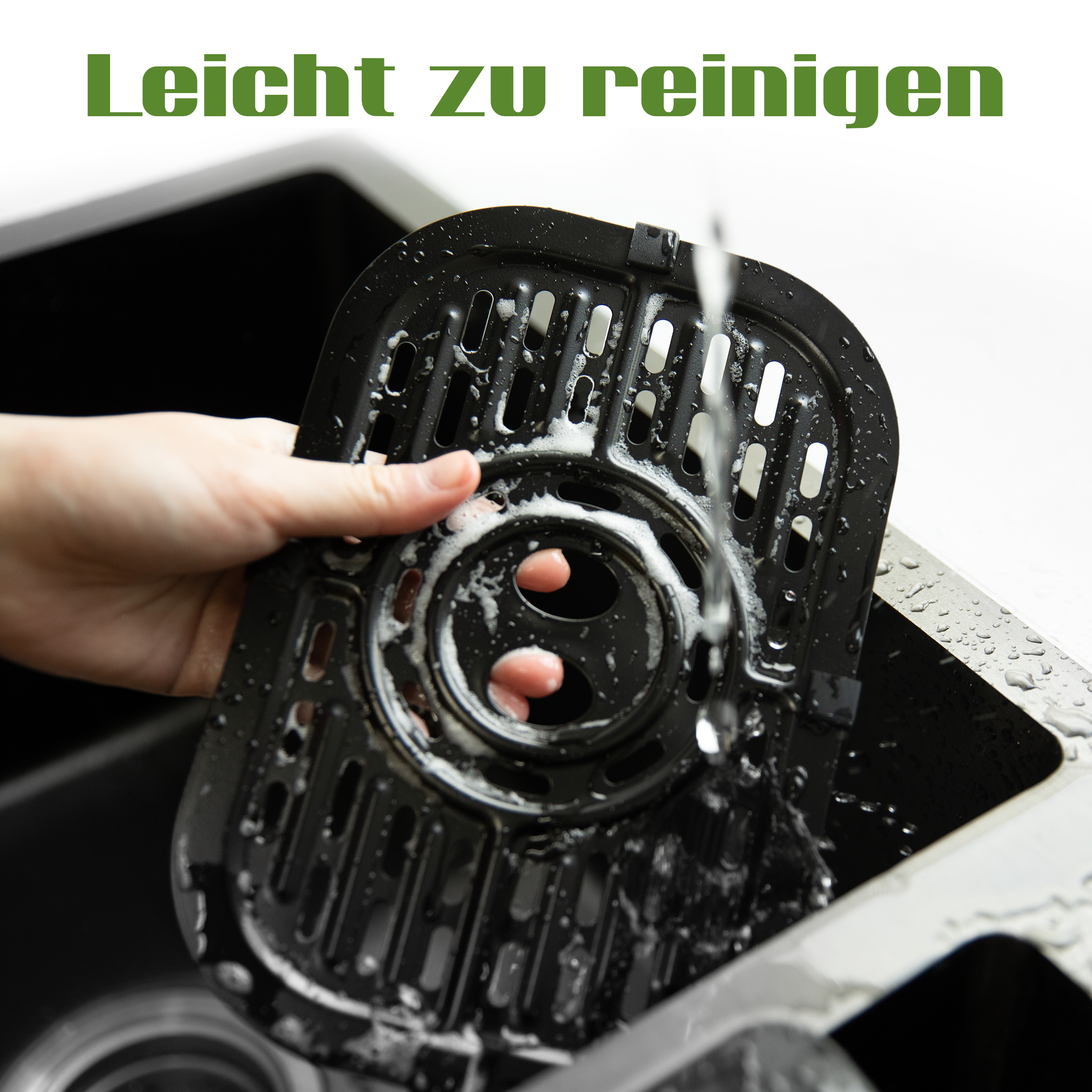 Hand wäscht einen schwarzen Frittierkorb in einem Waschbecken. Wasser fließt auf den Korb mit dem deutschen Text 'Leicht zu reinigen'.