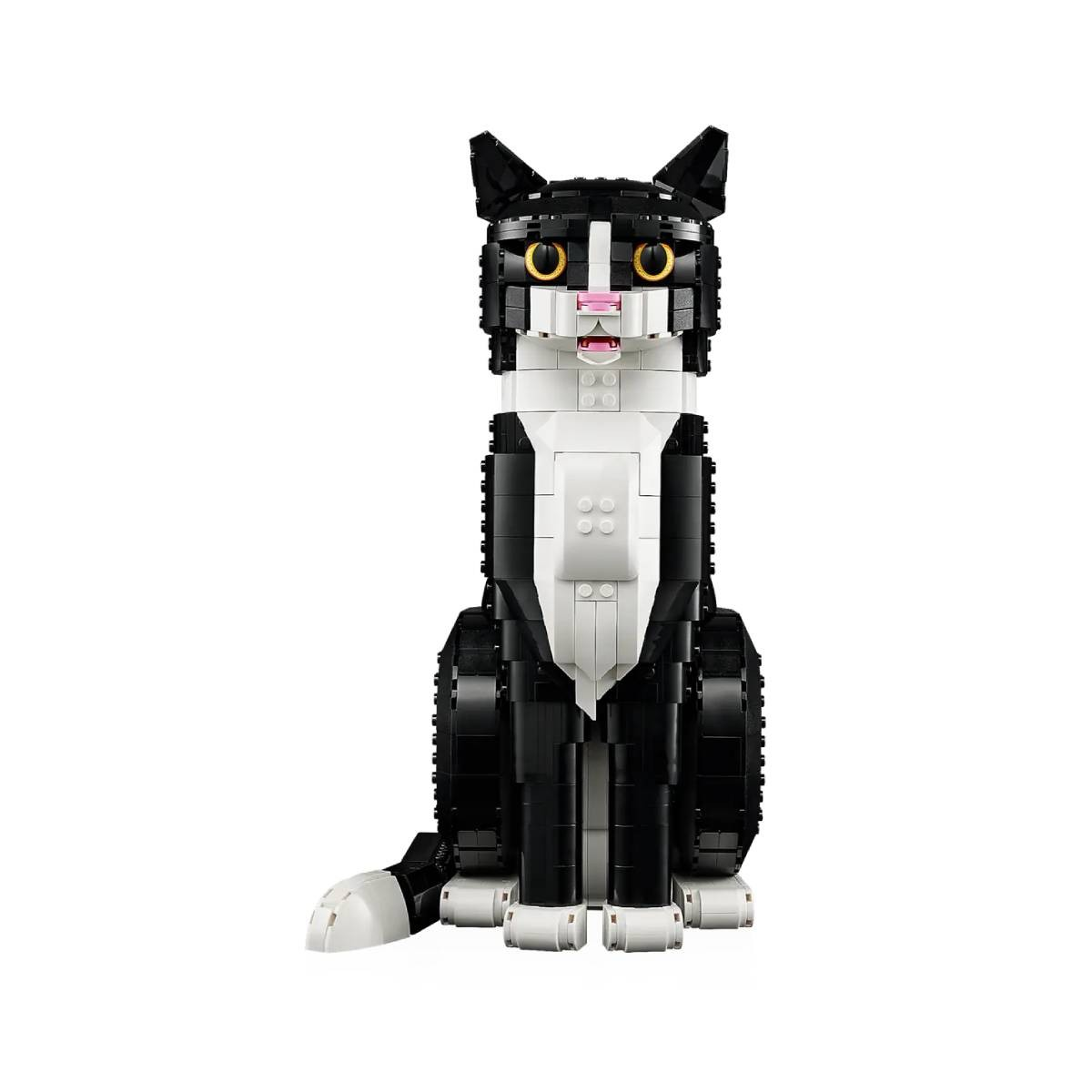 Kot Lego w czerni i bieli, siedzący prosto. Ma żółte oczy i różowy nos, na białym tle.