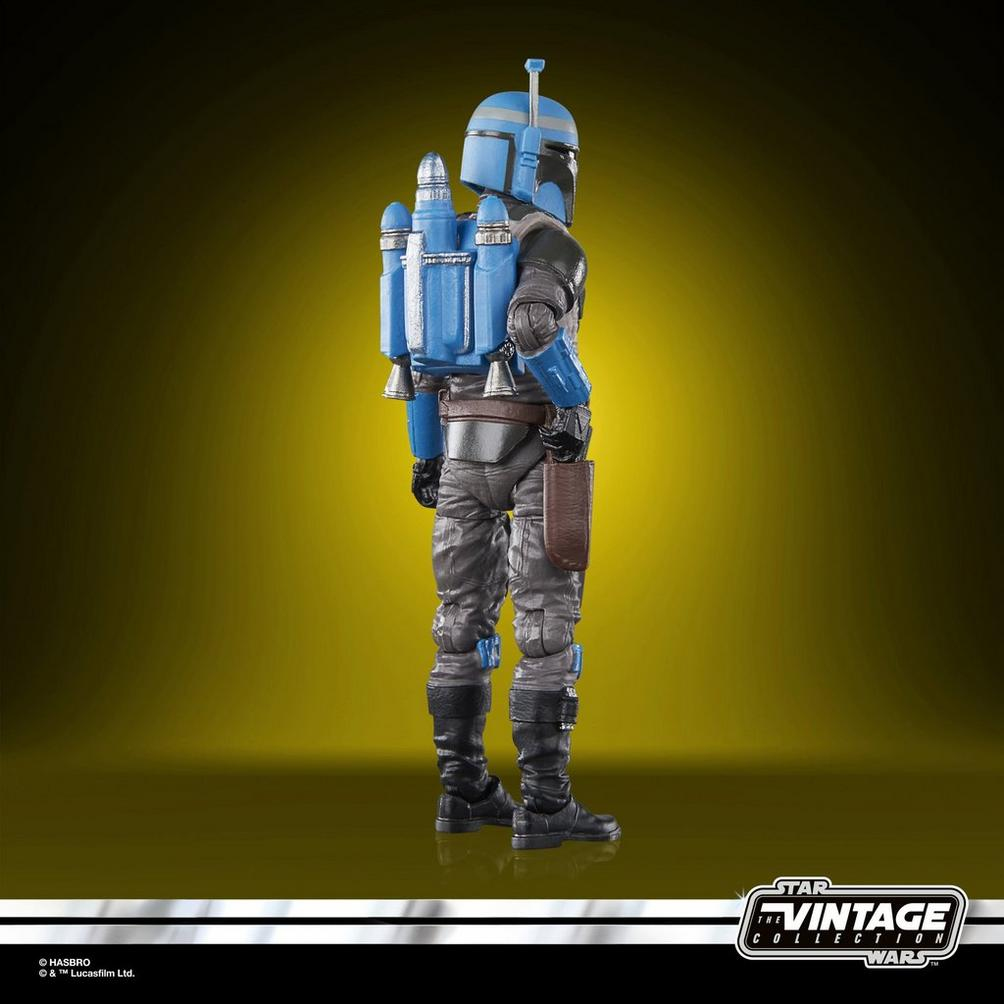 Mandaloryalı bir Star Wars aksiyon figürü, mavi kask ve jetpack, gri takım elbise ve siyah botlar. Sarı arka plan.