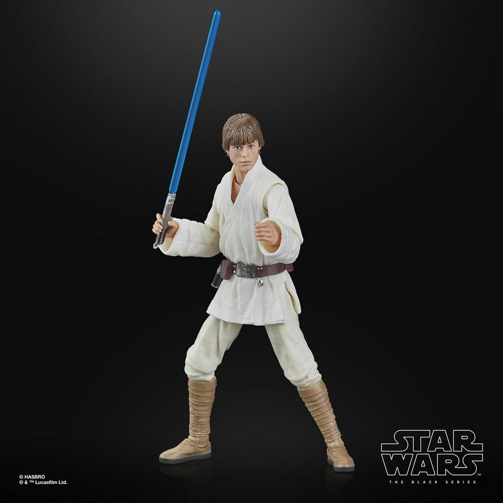 Mavi ışın kılıcı tutan Luke Skywalker'ın bir Star Wars aksiyon figürü. Beyaz bir kıyafet giyiyor ve siyah bir zemin üzerinde duruyor.