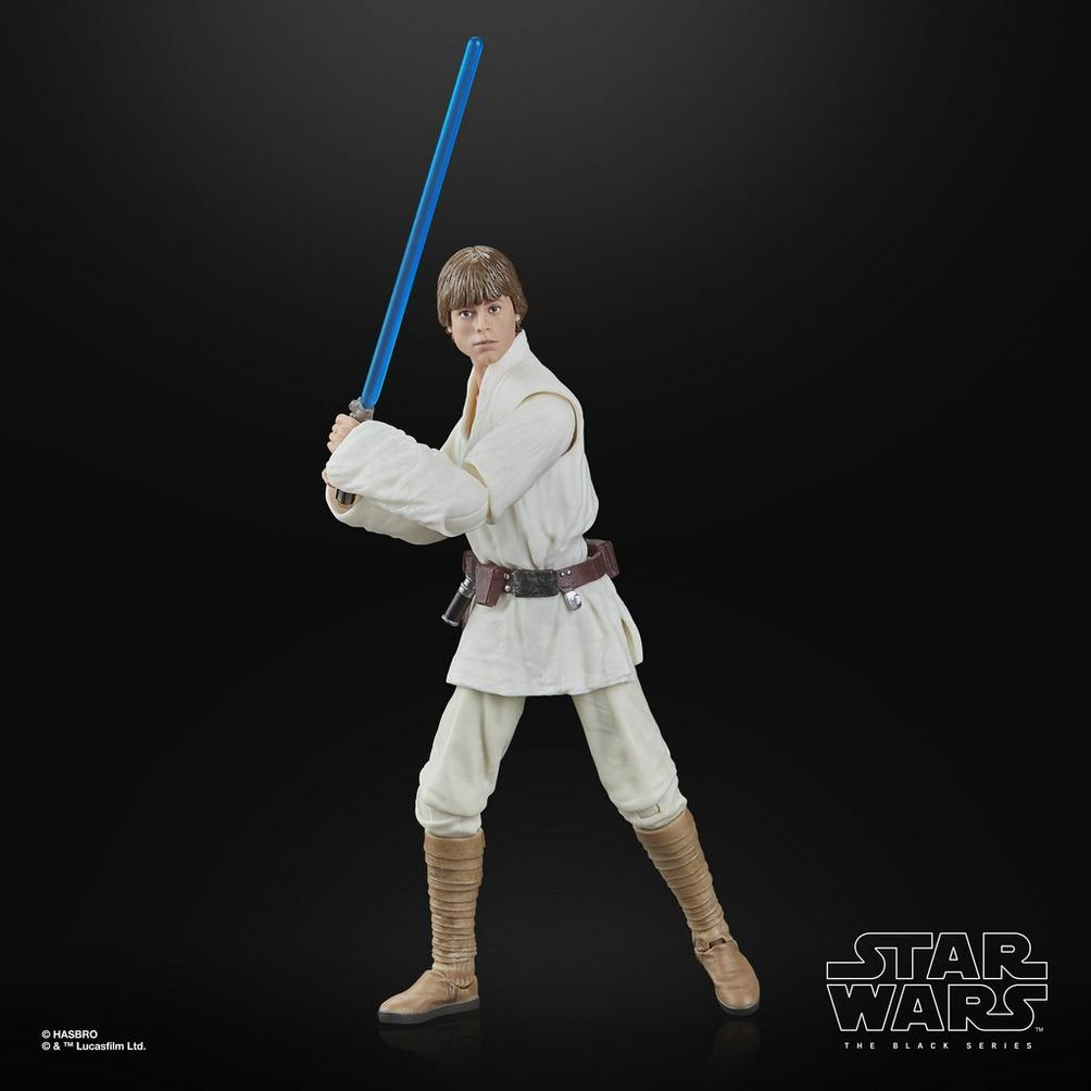 Mavi ışın kılıcı tutan, beyaz tunik ve pantolon giymiş, kahverengi botları ve kemeri olan Luke Skywalker figürü.