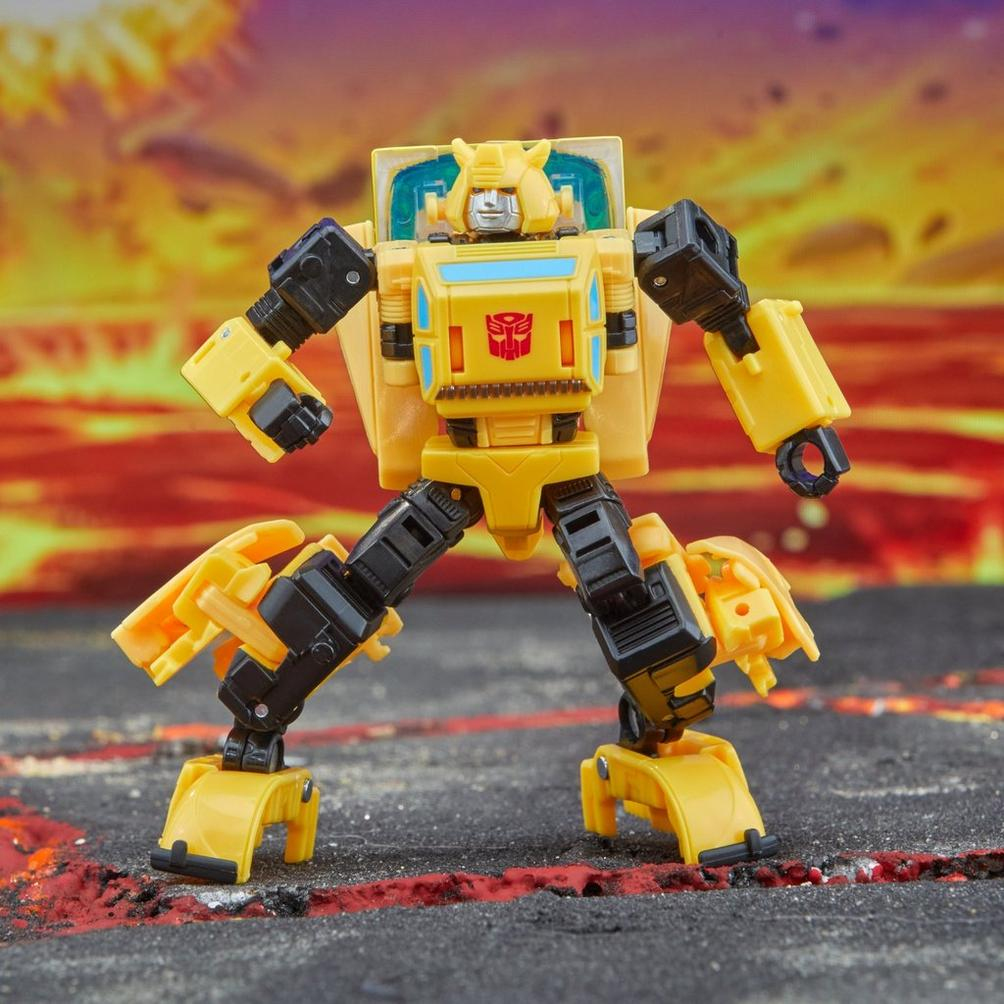 Un giocattolo Transformer giallo e nero è in posa di battaglia su una superficie strutturata. Lo sfondo ha colori infuocati.