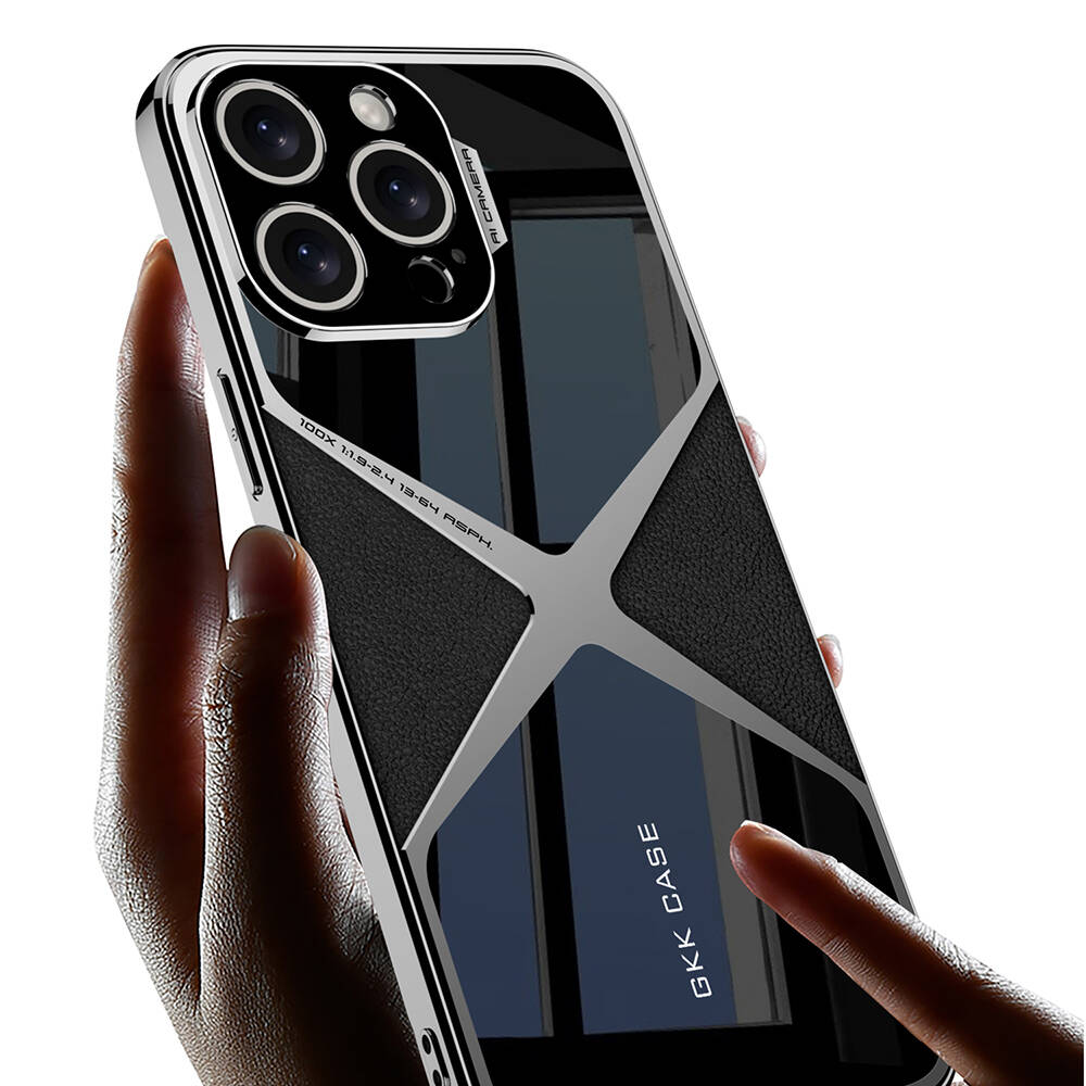 Bir el, gümüş çerçeveli ve siyah dokulu arka yüzü olan bir telefon kılıfı tutuyor. Kılıfın kamera boşlukları ve yansıtıcı bir yüzeyi var.
