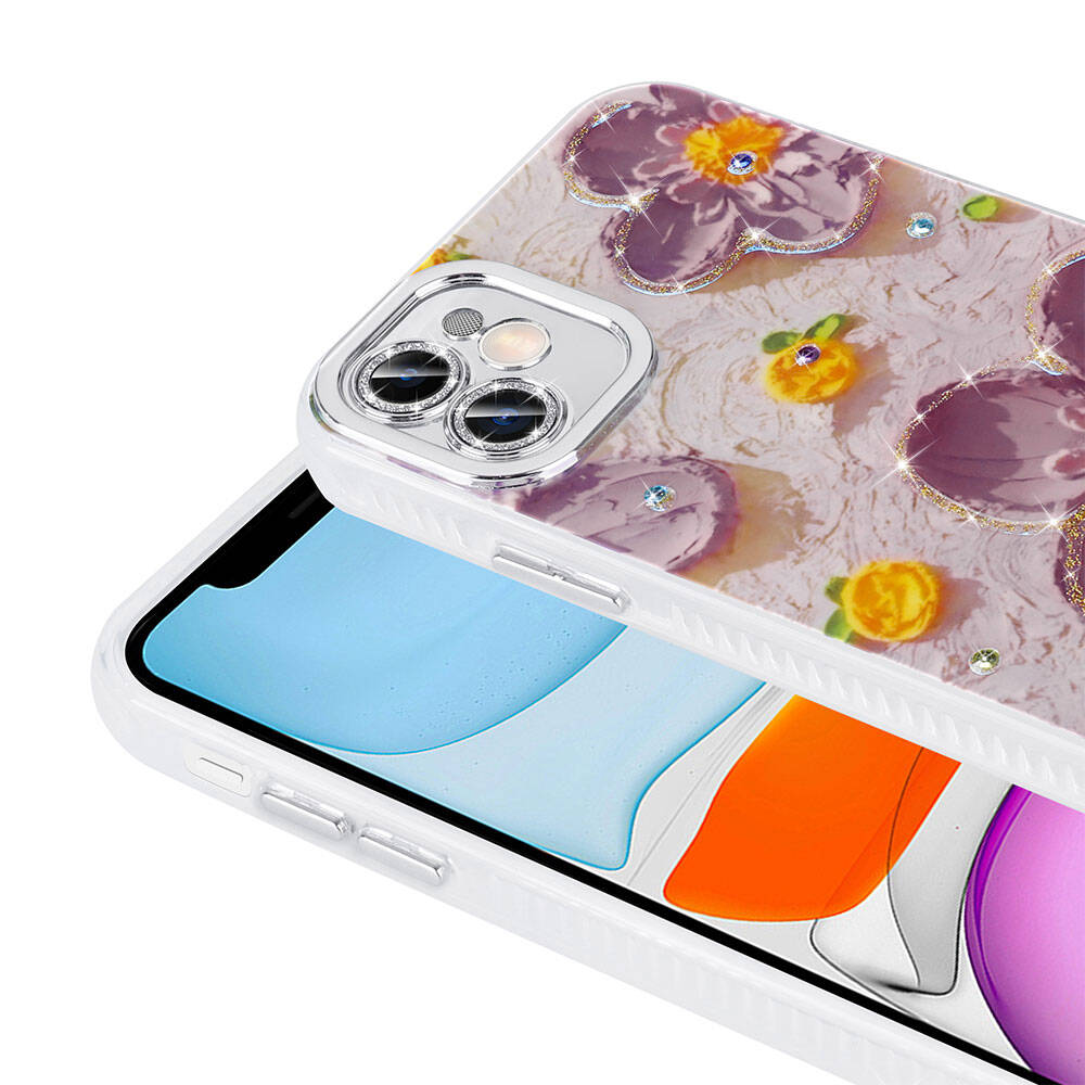 Çiçek desenli bir telefon kılıfı. Kılıf beyazdır ve mor çiçek desenine sahiptir. Telefonun gümüş bir kamerası vardır.