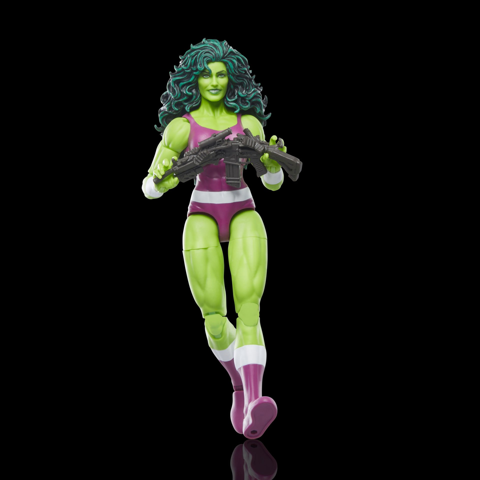 Bir She-Hulk aksiyon figürü, bir makineli tüfek tutuyor. Yeşil tenli, mor ve beyaz bir kıyafet giyiyor, yeşil saçlı.
