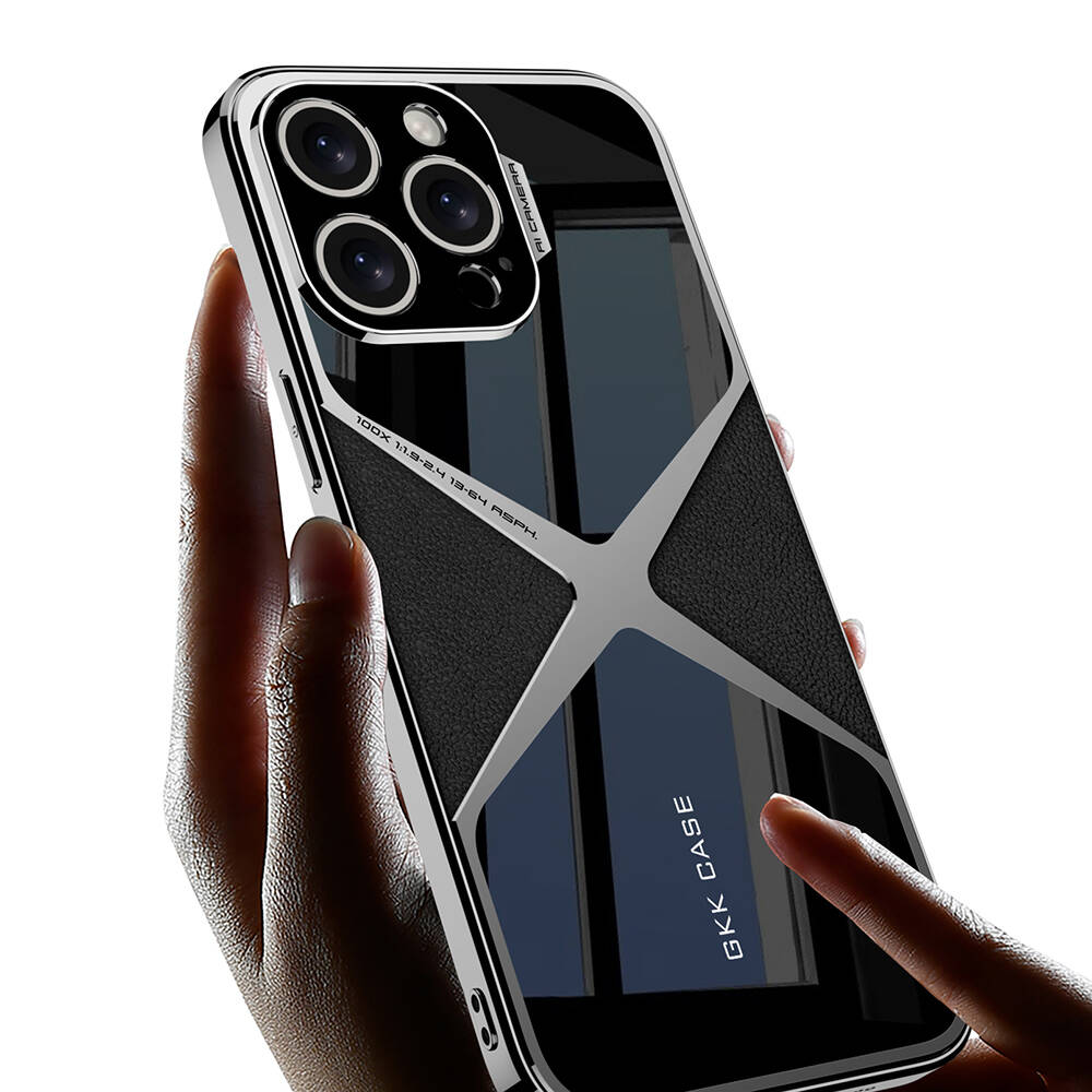 Bir el, bir kılıfla birlikte bir telefon tutuyor. Kılıfın gümüş bir çerçevesi, siyah derisi ve cam bir arka yüzü var. Telefondan birden fazla kamera var.