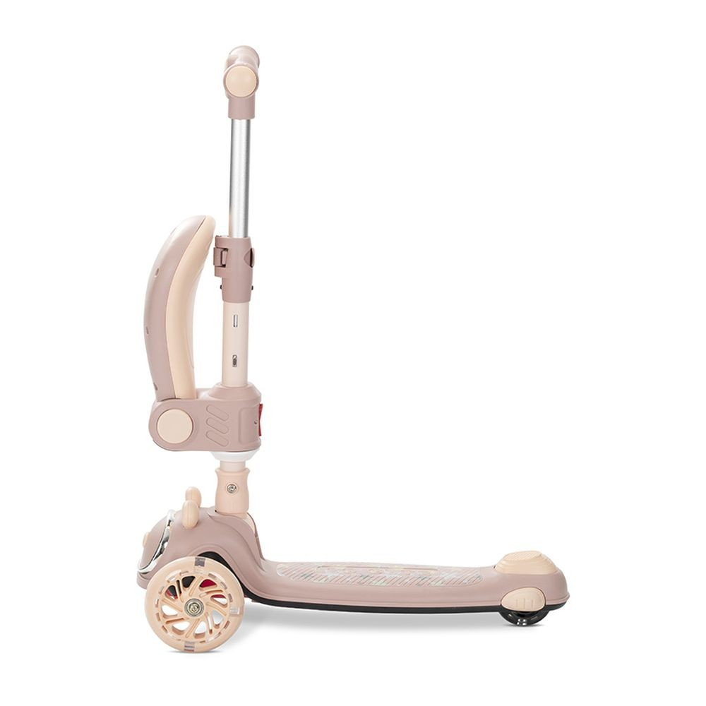 Un patinete beige y rosa. Tiene tres ruedas, un manillar y una plataforma. El patinete está sobre un fondo blanco.