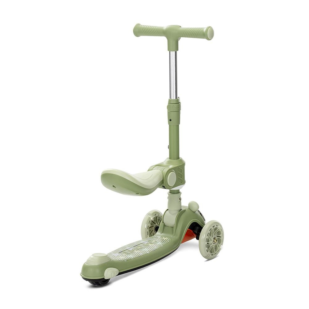 Un patinete verde con asiento y tres ruedas. Tiene un manillar en forma de T y una plataforma. El fondo es blanco.
