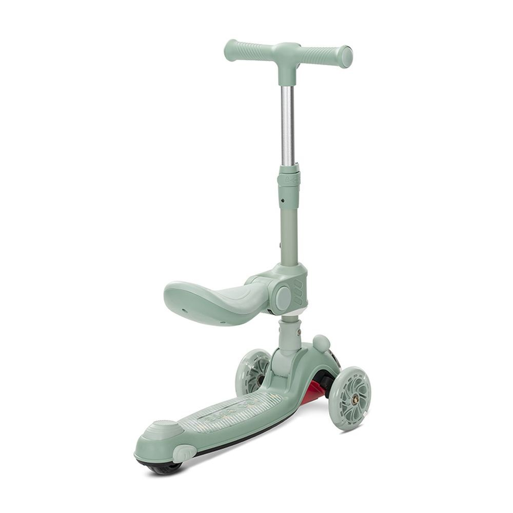 Un patinete verde claro con tres ruedas, un asiento y un manillar. El patinete está sobre un fondo blanco.