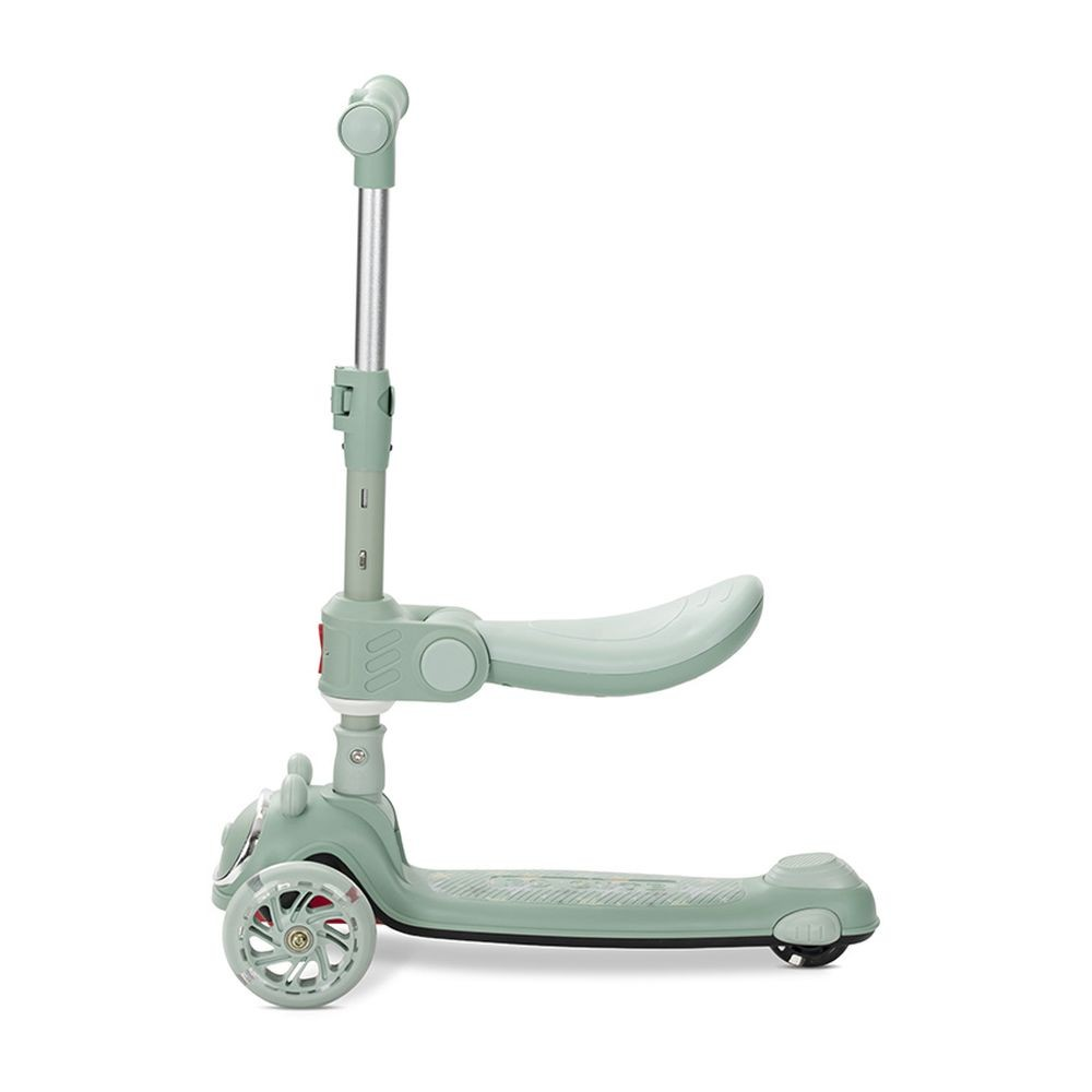 Un patinete verde claro con tres ruedas. Tiene asiento, manillar y plataforma. El fondo es blanco.