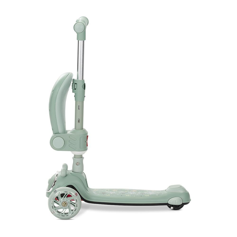 Un patinete verde menta con tres ruedas. Tiene un manillar, una plataforma para los pies y un accesorio para el asiento en el lateral. El fondo es blanco.