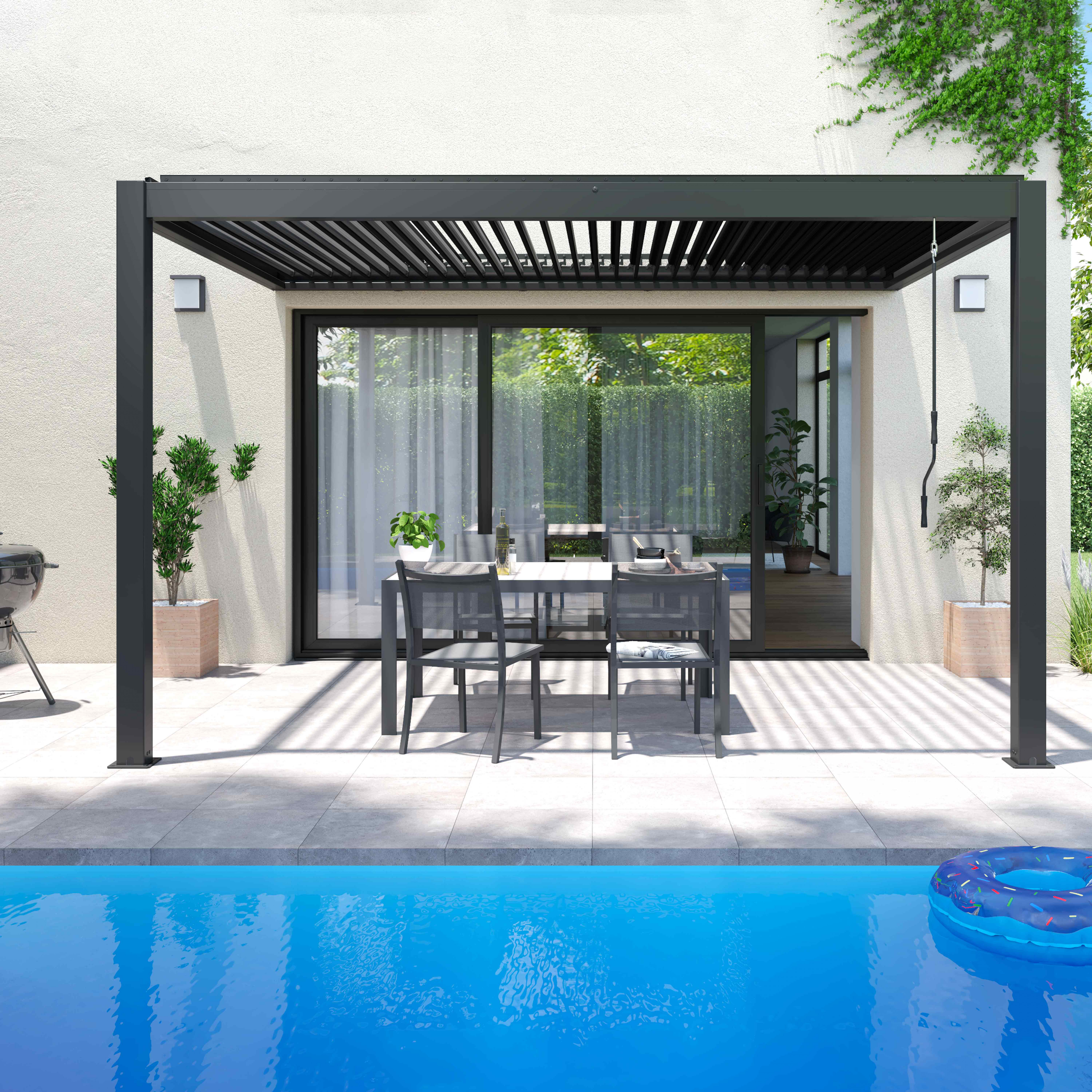 Terrasse mit Pool. Tisch mit Stühlen, Pergola, Pflanzen und Pool-Schwimmer im blauen Pool. Weiße Wand und grüne Bäume im Hintergrund.