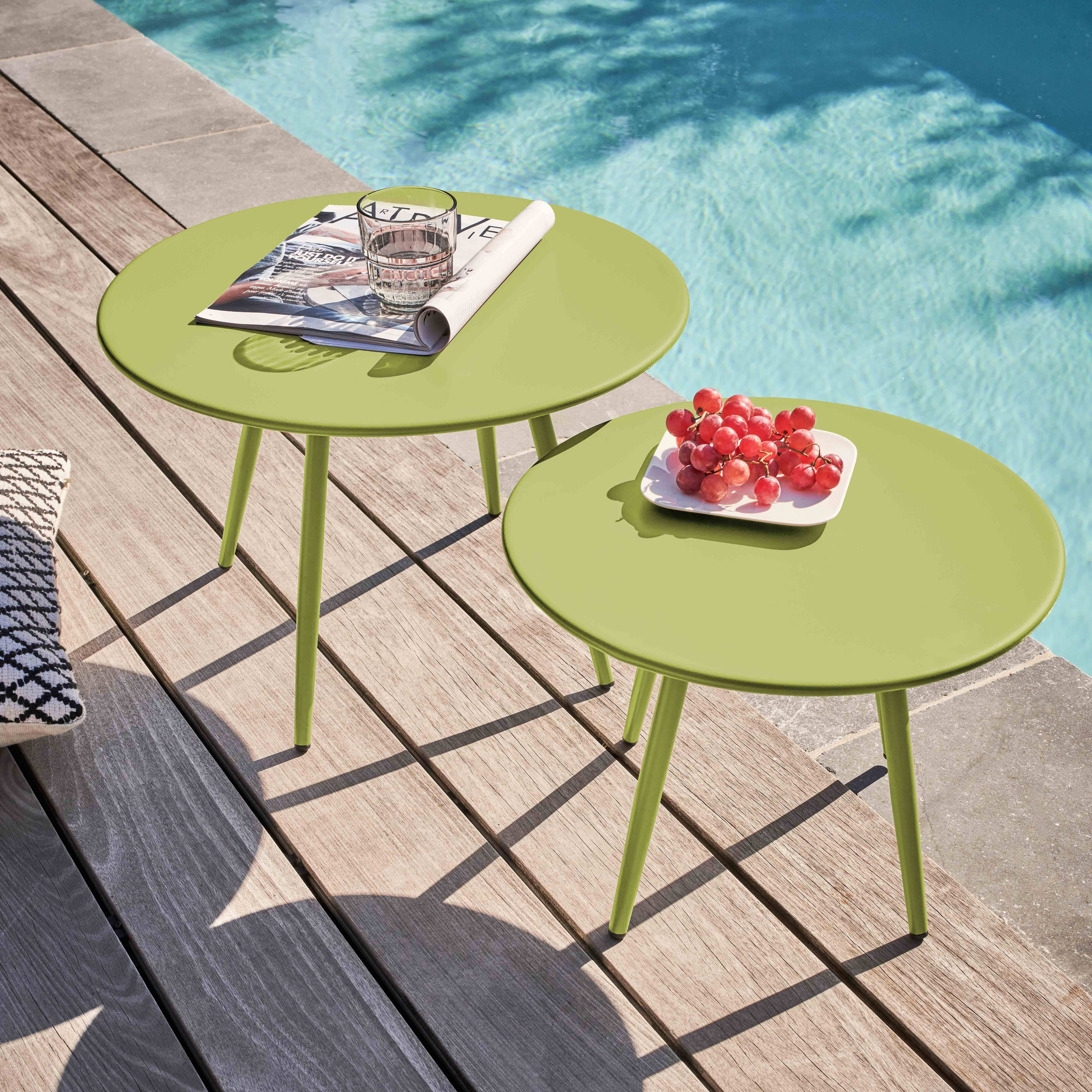 Zwei grüne Tische mit Trauben und einem Glas am Pool. Ein Tisch hat eine Zeitschrift. Holzdeck im Vordergrund.
