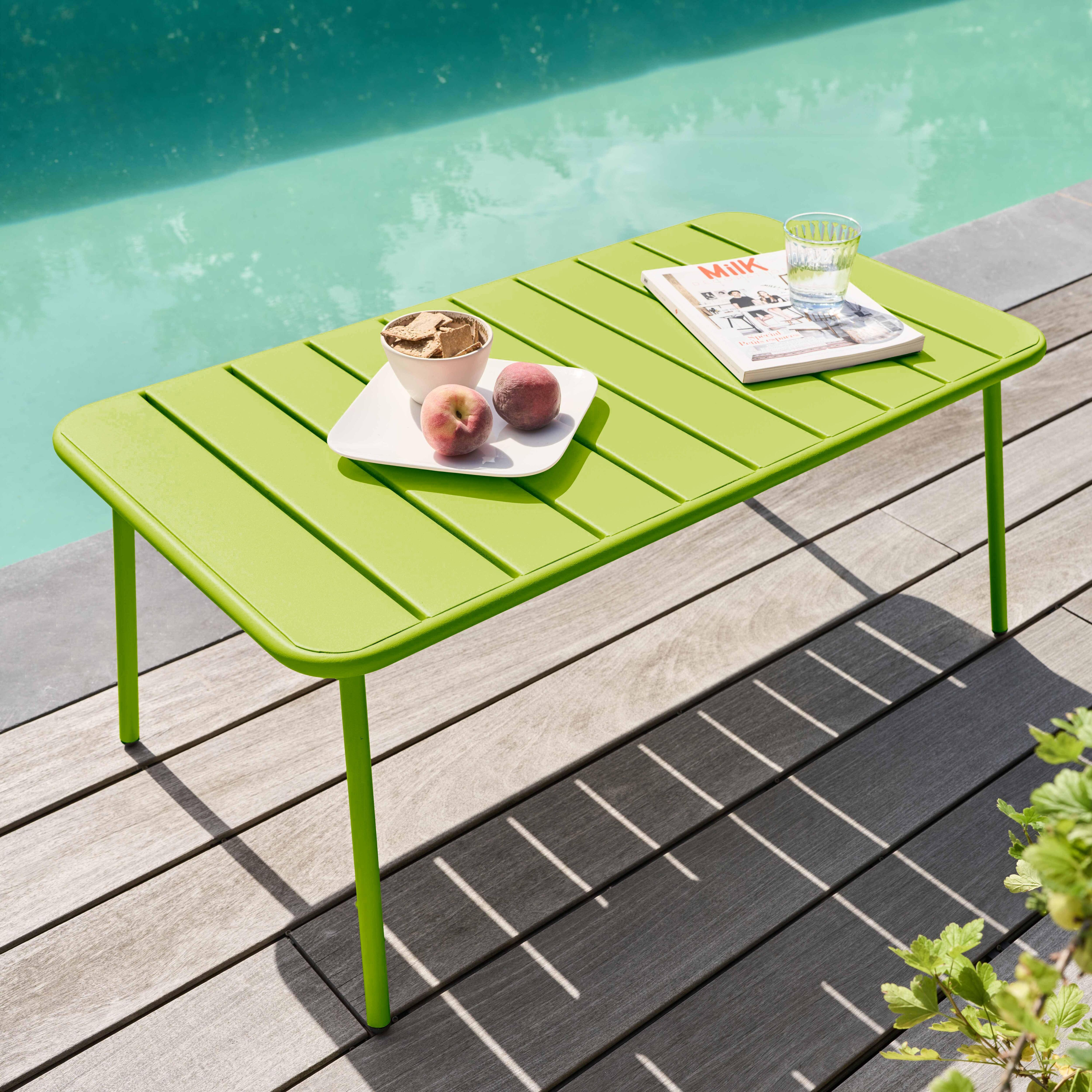 Grüner Tisch mit Snacks und Pfirsichen in der Nähe eines Pools. Zeitschrift und Glas liegen auch auf dem Tisch.