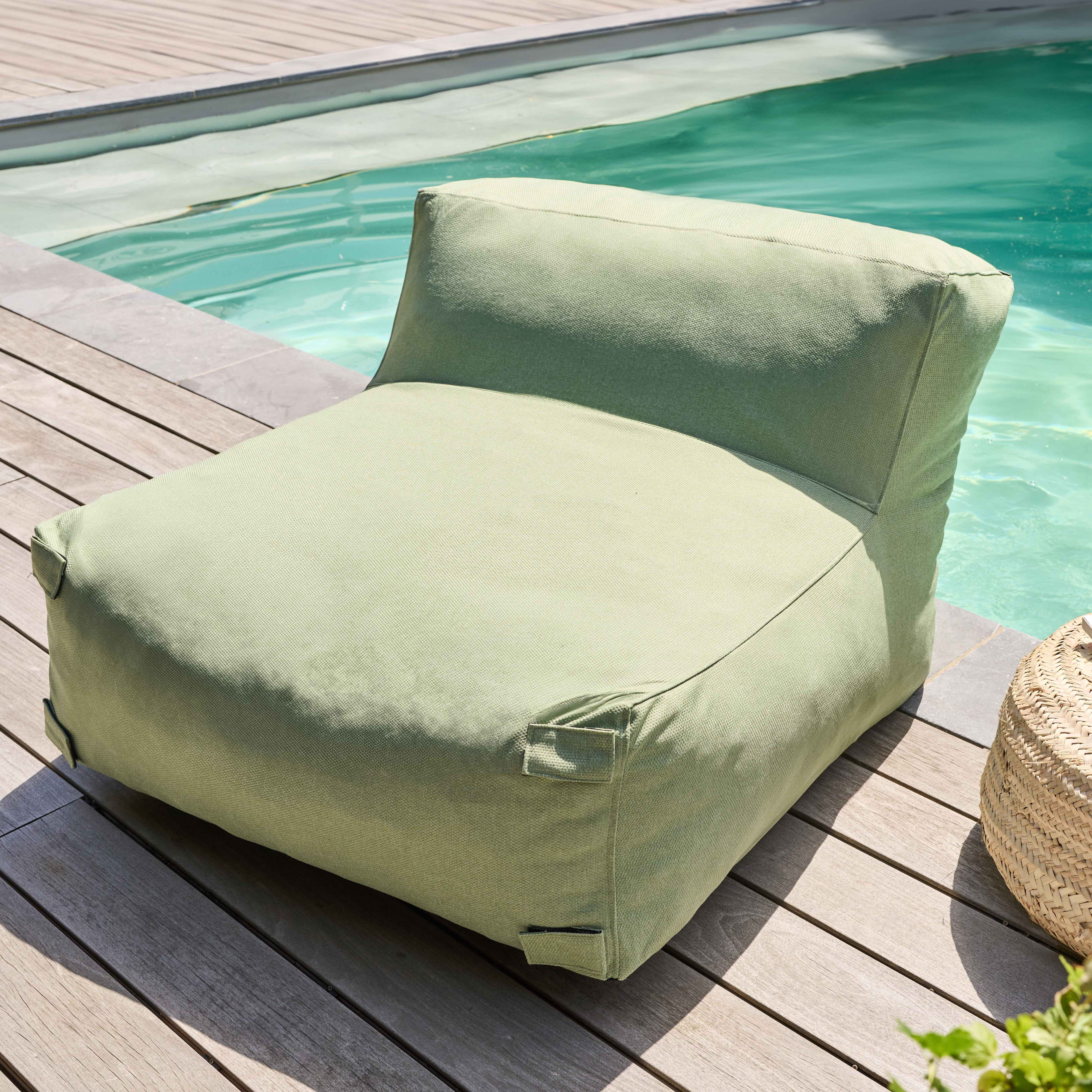 Ein grüner Loungesessel steht auf einem Holzdeck neben einem Pool. Ein Weidenkorb ist in der Nähe.