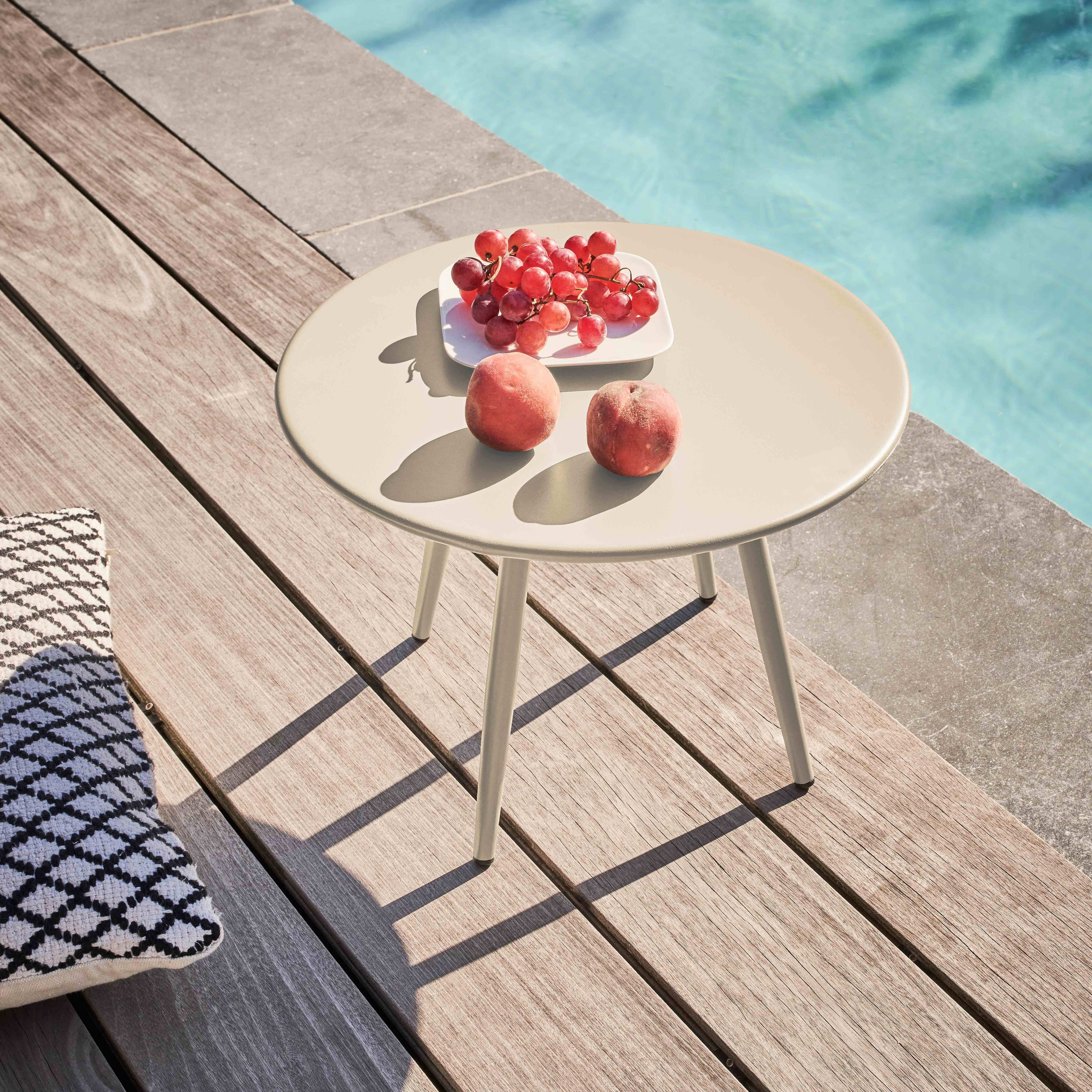 Ein Tisch mit Trauben und Pfirsichen steht auf einem Holzdeck neben einem Pool. Ein gemustertes Kissen ist ebenfalls sichtbar.
