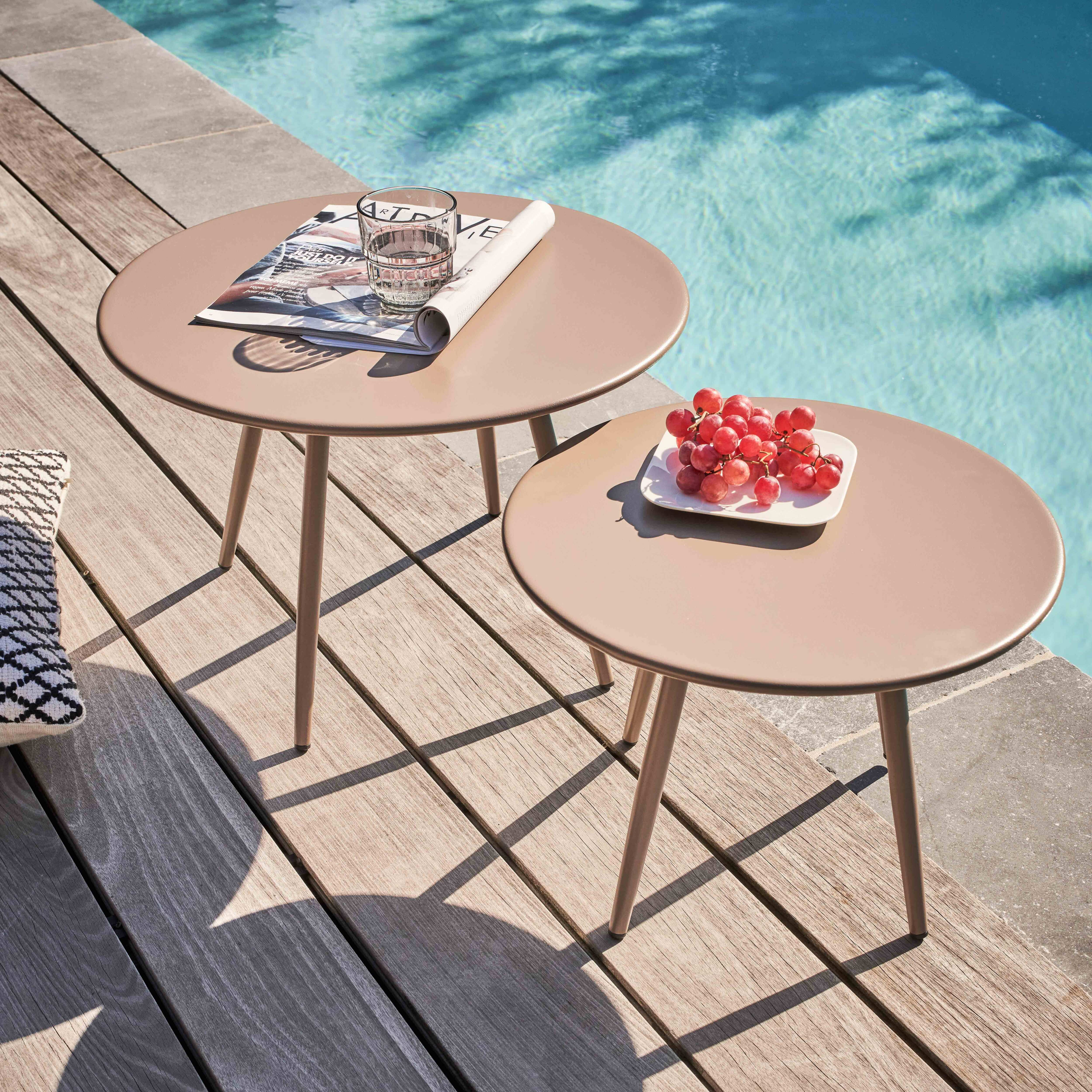 Zwei kleine Tische mit Gegenständen auf Holzdeck neben einem Pool. Trauben und ein Glas sind sichtbar.