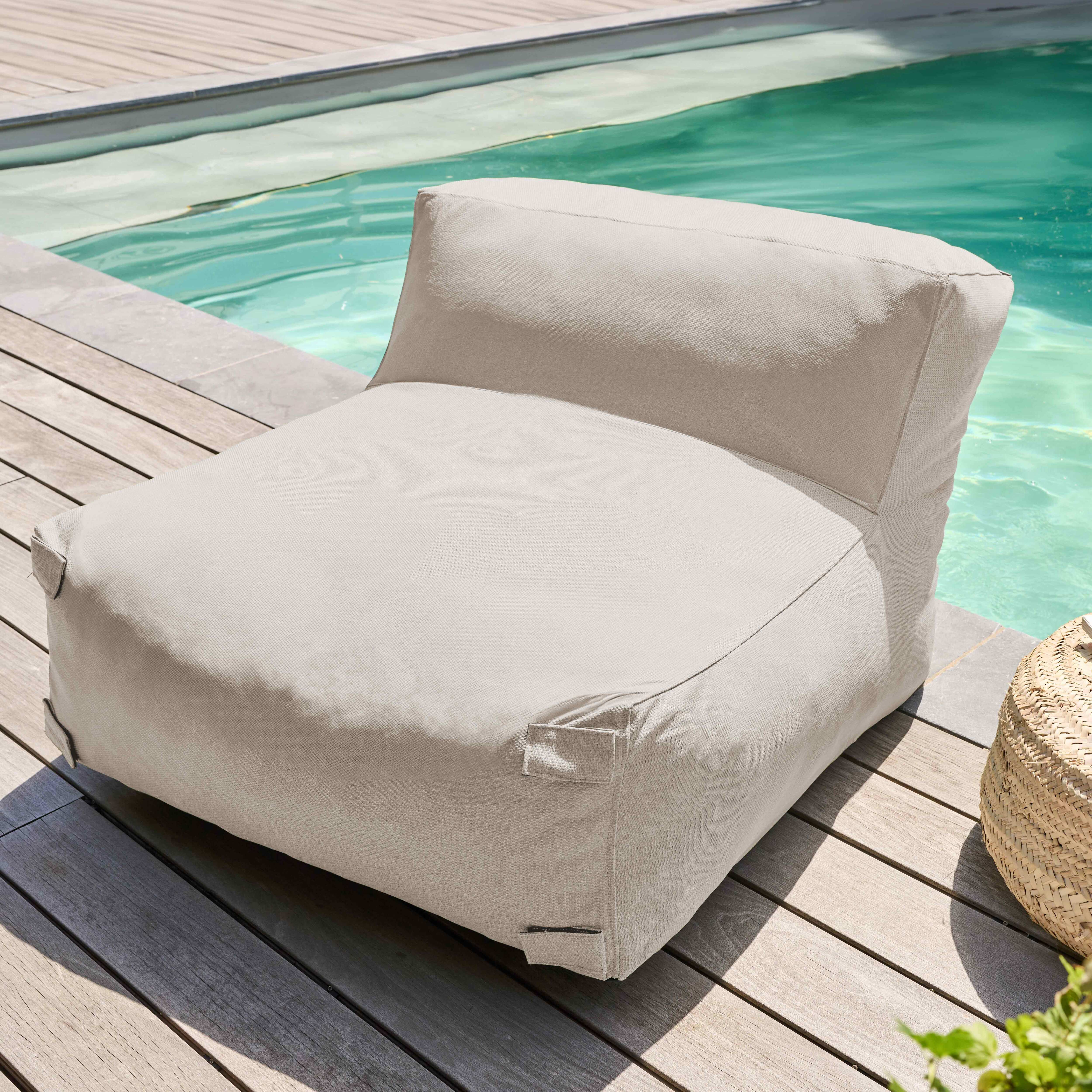 Ein beiger Outdoor-Sitzsack steht am Pool. Im Hintergrund befinden sich Wasser und ein Weidenkorb.