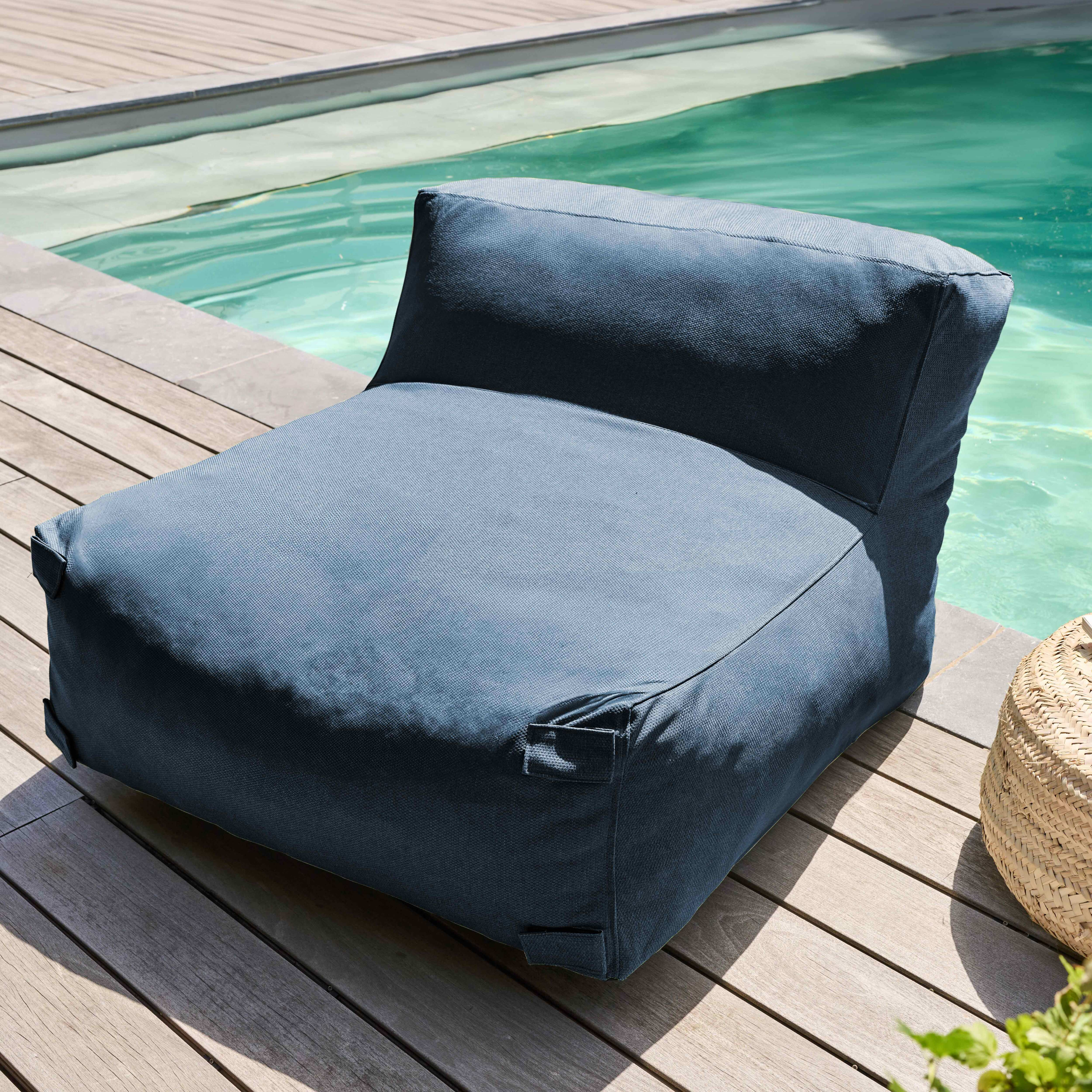 Ein blauer Sitzsack steht auf einem Holzdeck neben einem Pool. Rechts ist ein geflochtener Korb.