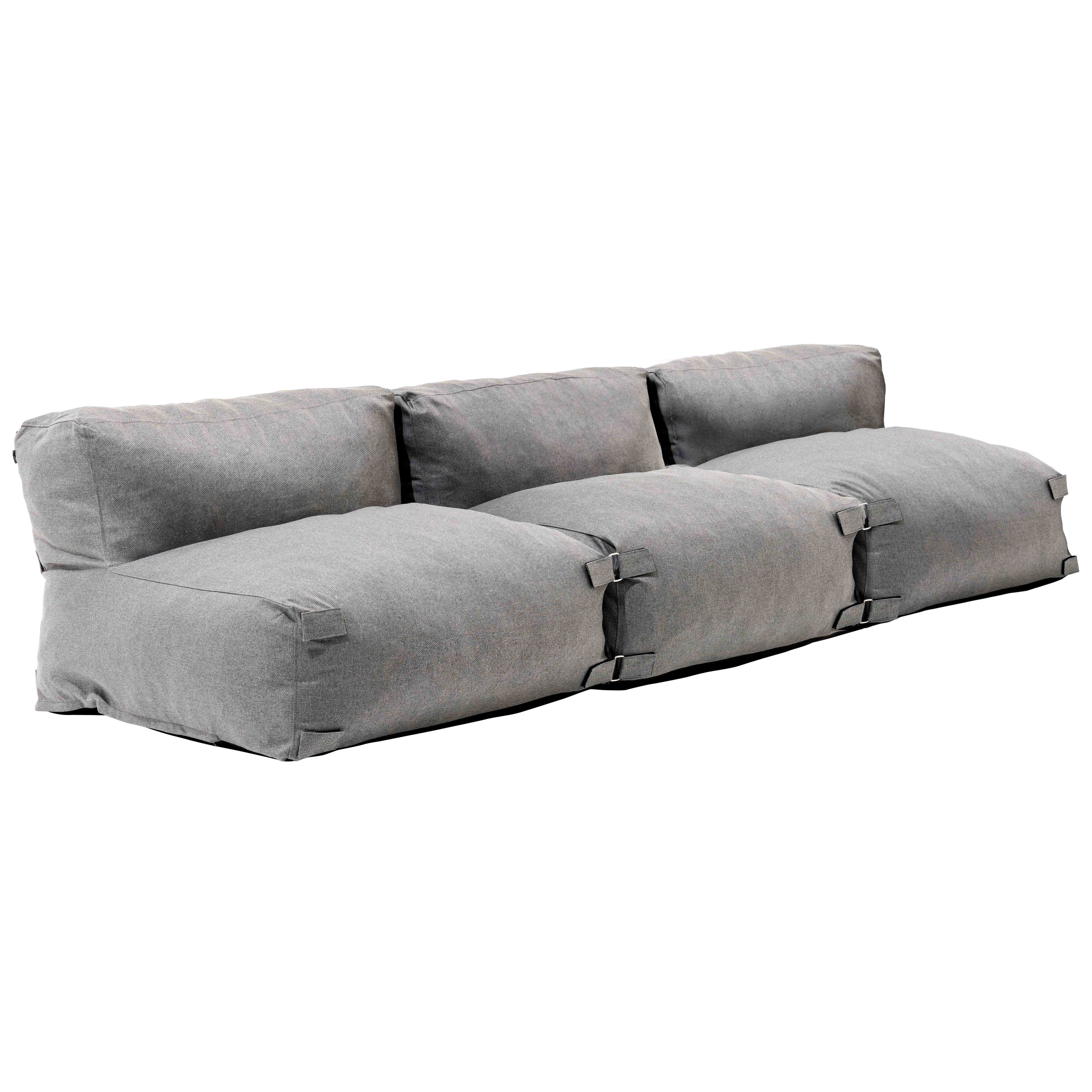 Ein graues Modulsofa ist auf Weiß isoliert. Es hat drei Abschnitte, jeweils mit Sitz und Rückenlehne und Metallschnallen.