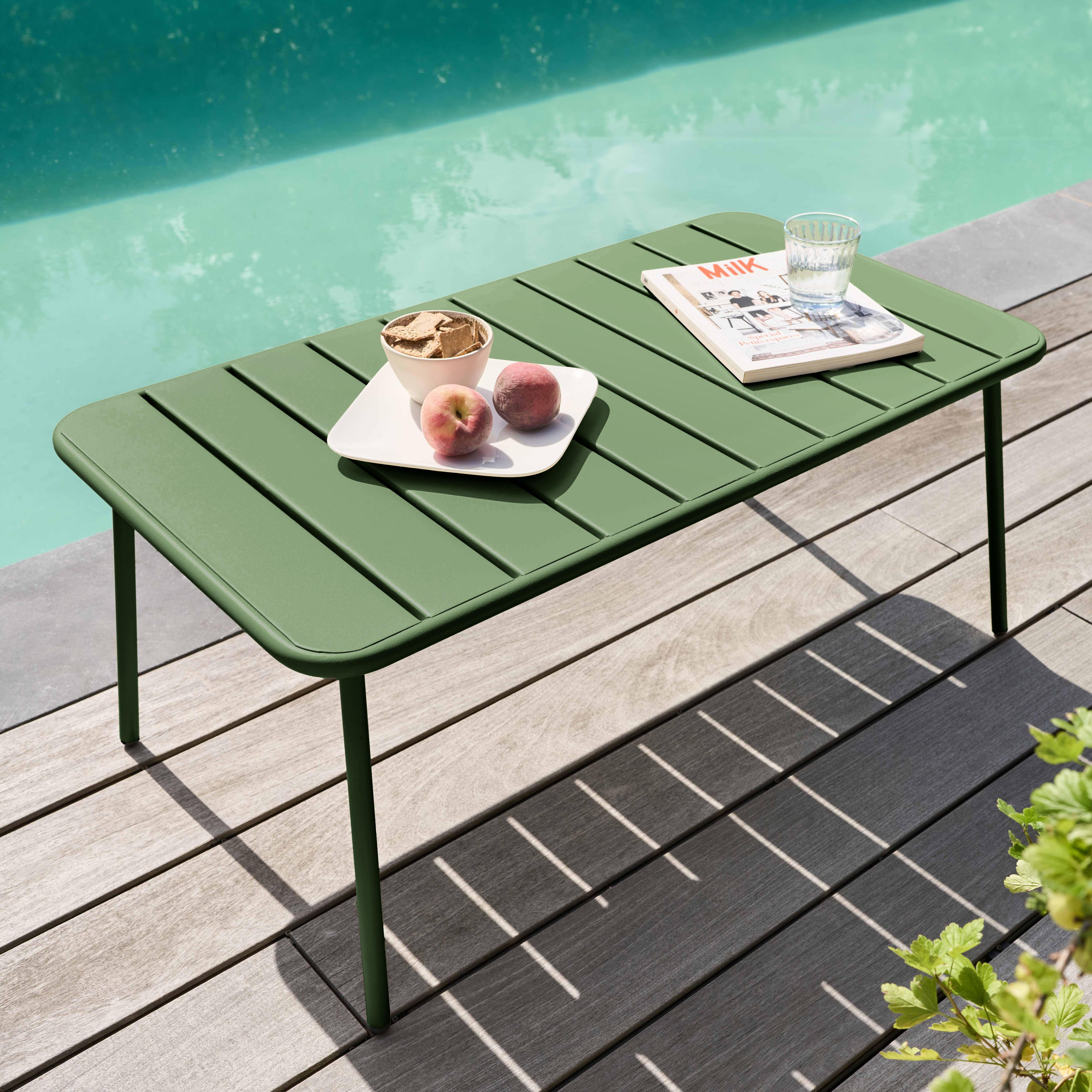 Ein grüner Tisch mit Essen und einer Zeitschrift steht am Pool. Pfirsiche und Cracker liegen auf dem Tisch.