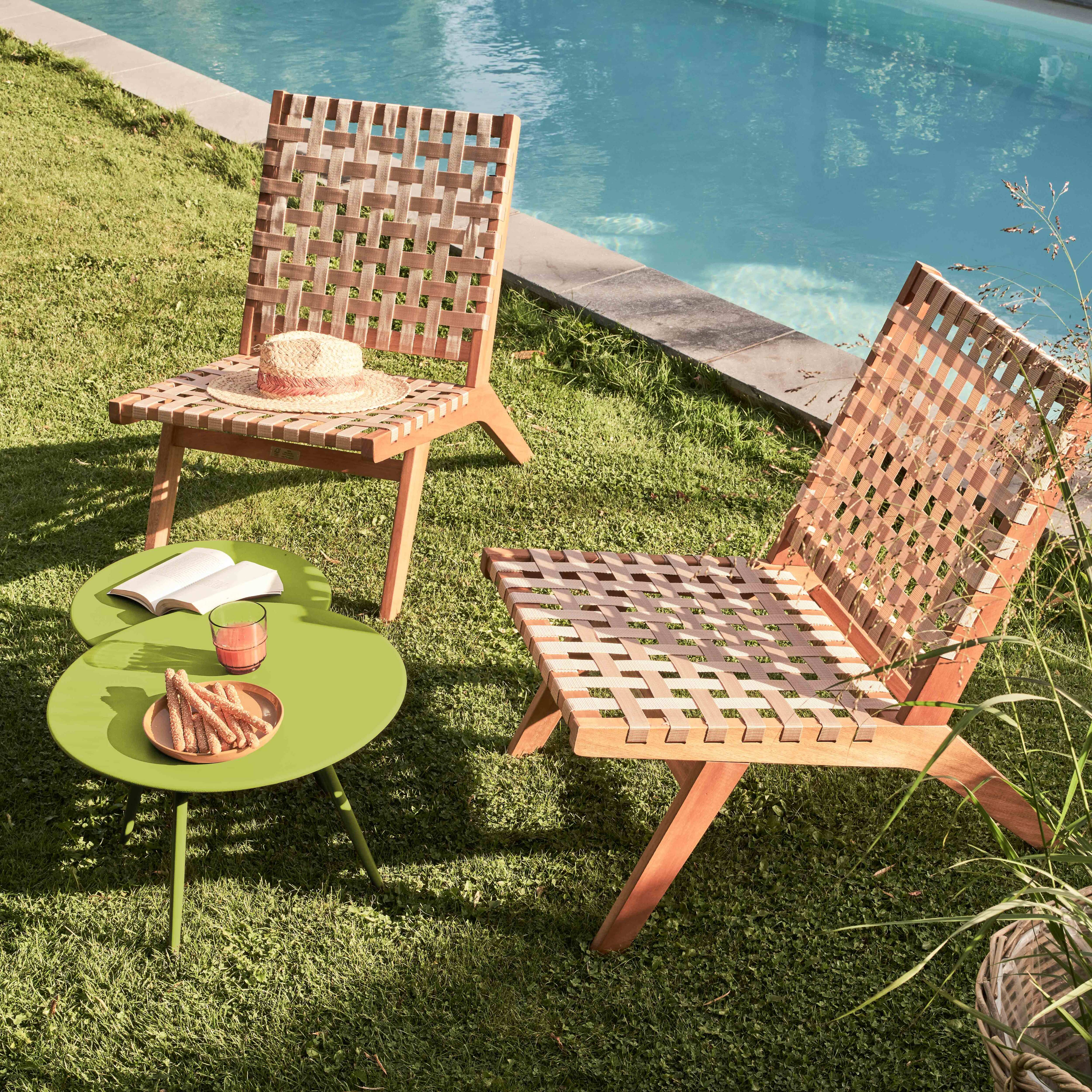 Zwei Stühle, ein Tisch mit Essen und ein Pool im Hintergrund. Die Szene spielt auf grünem Gras.