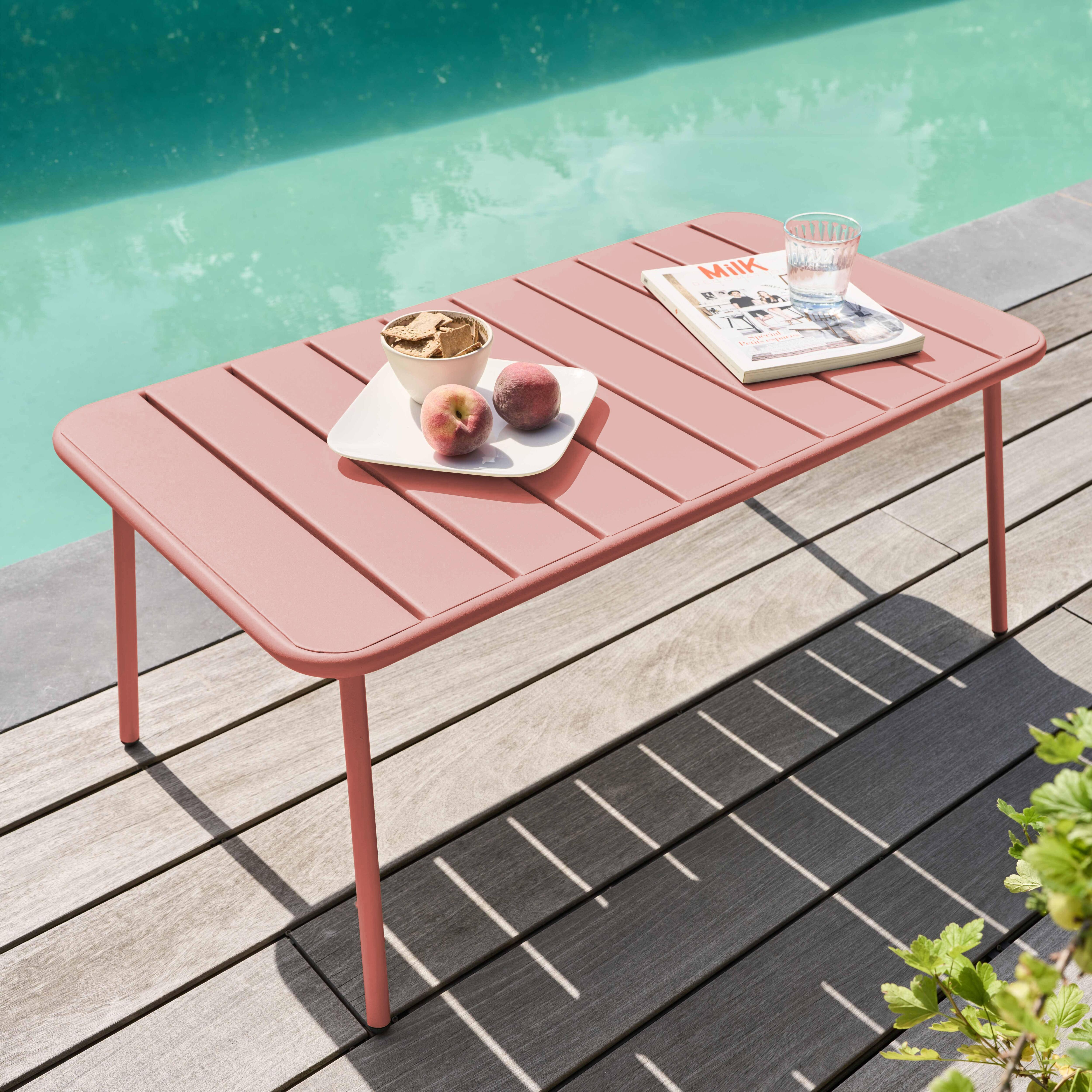 Ein rosa Tisch mit Speisen und Getränken steht neben einem Pool. Pfirsiche, Cracker und ein Glas Wasser stehen auf dem Tisch.