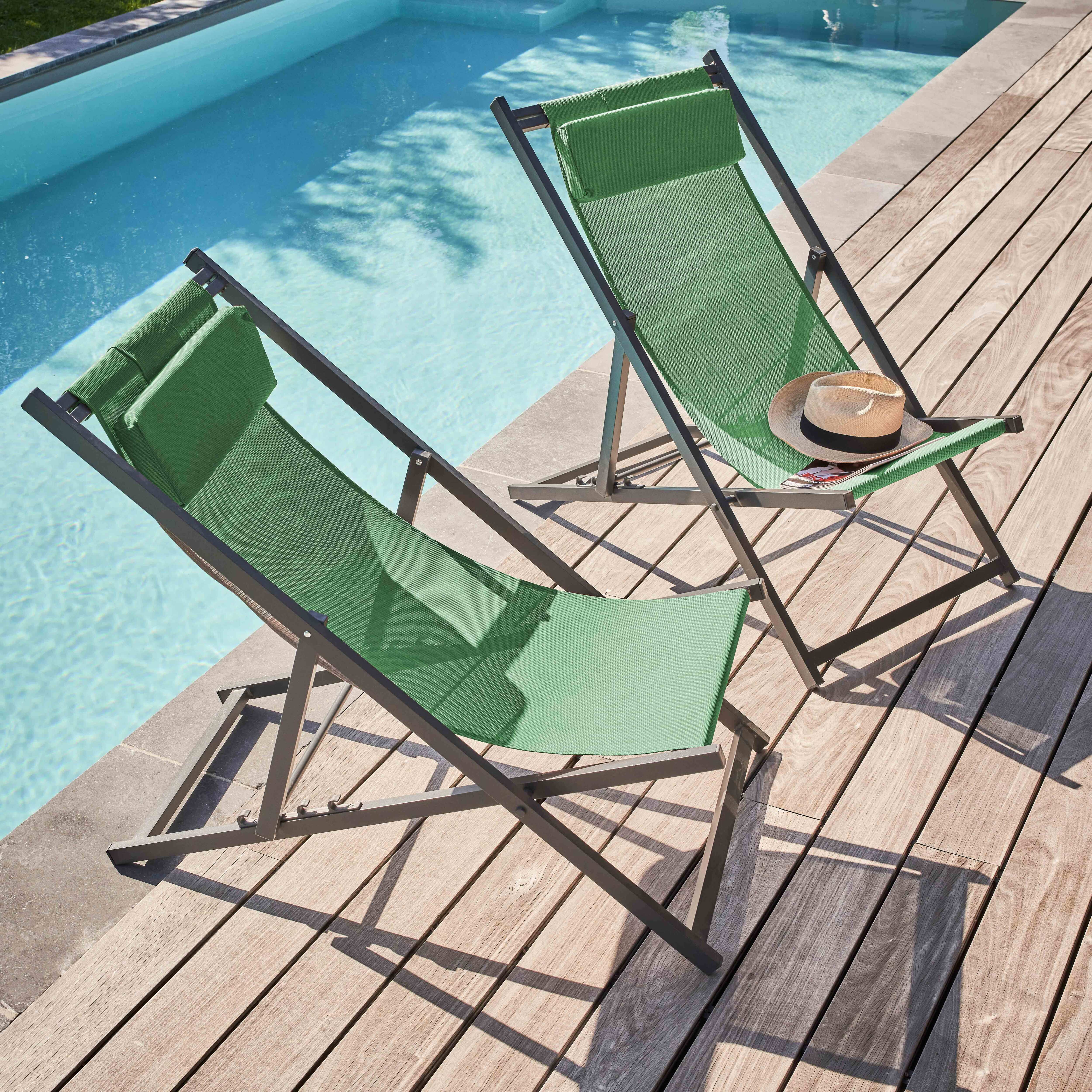Zwei grüne Liegestühle, ein Hut und ein Pool. Stühle stehen auf Holz, Pool hat blaues Wasser.
