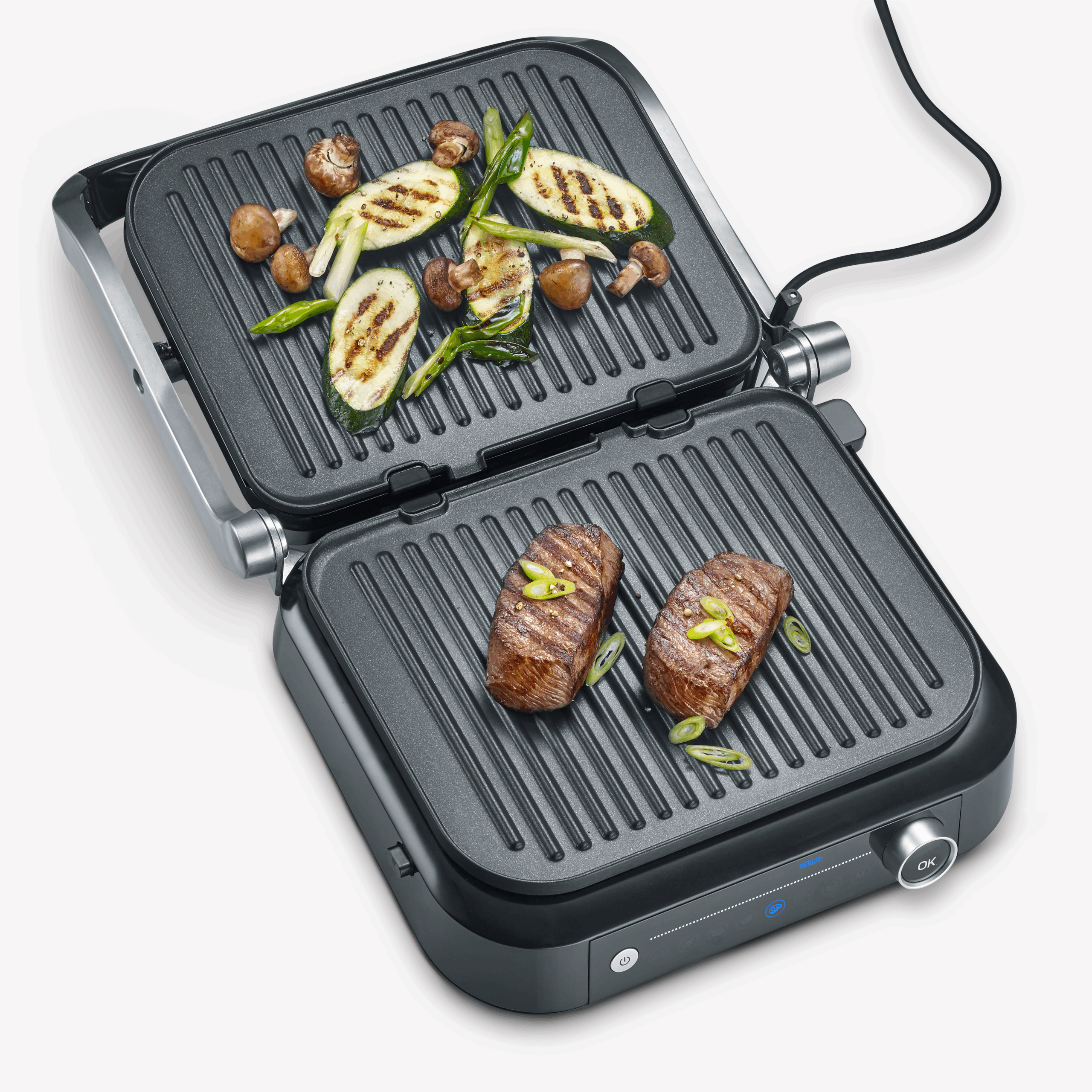 Grill met gegrilde groenten en steaks. De grill is open, met eten. Witte achtergrond.