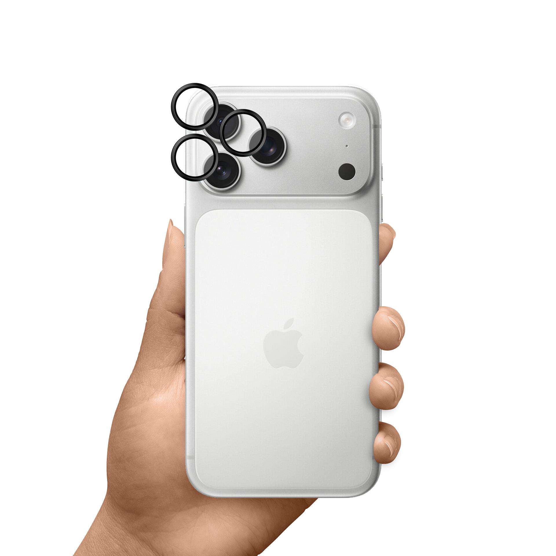 Biały iPhone trzymany w dłoni, widok z tyłu z osłoną obiektywu aparatu. Logo Apple jest widoczne. Tło jest białe.