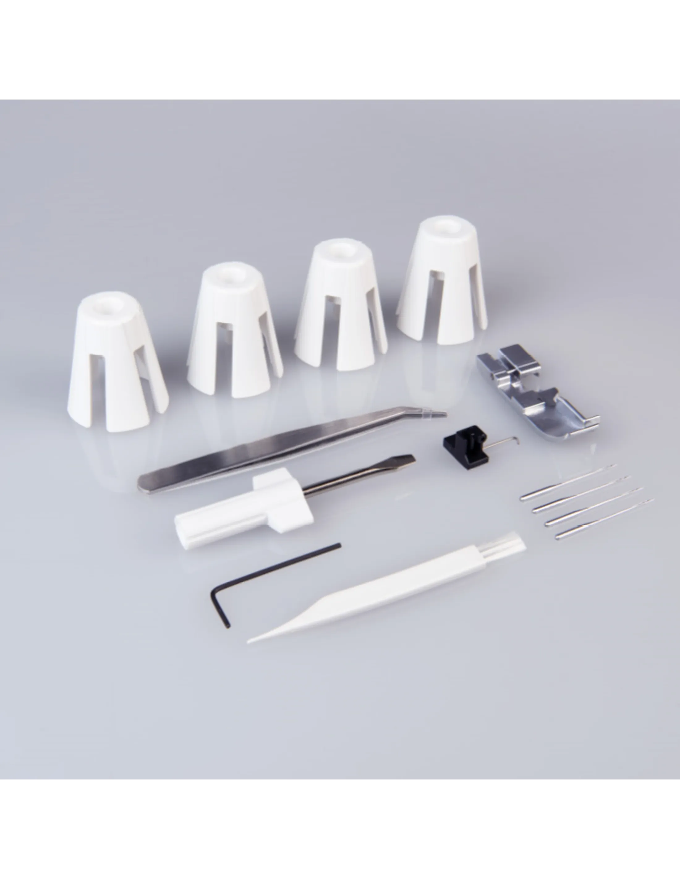 Accessoires de machine à coudre sur une surface grise. Comprend des cônes blancs, pinces, tournevis et petits outils.
