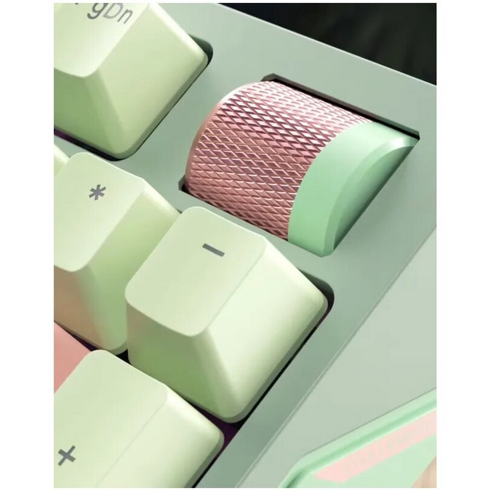 Zbliżenie klawiatury. Jasnozielone klawisze z symbolami. Różowo-zielone pokrętło pośrodku, klawisze ułożone po przekątnej.