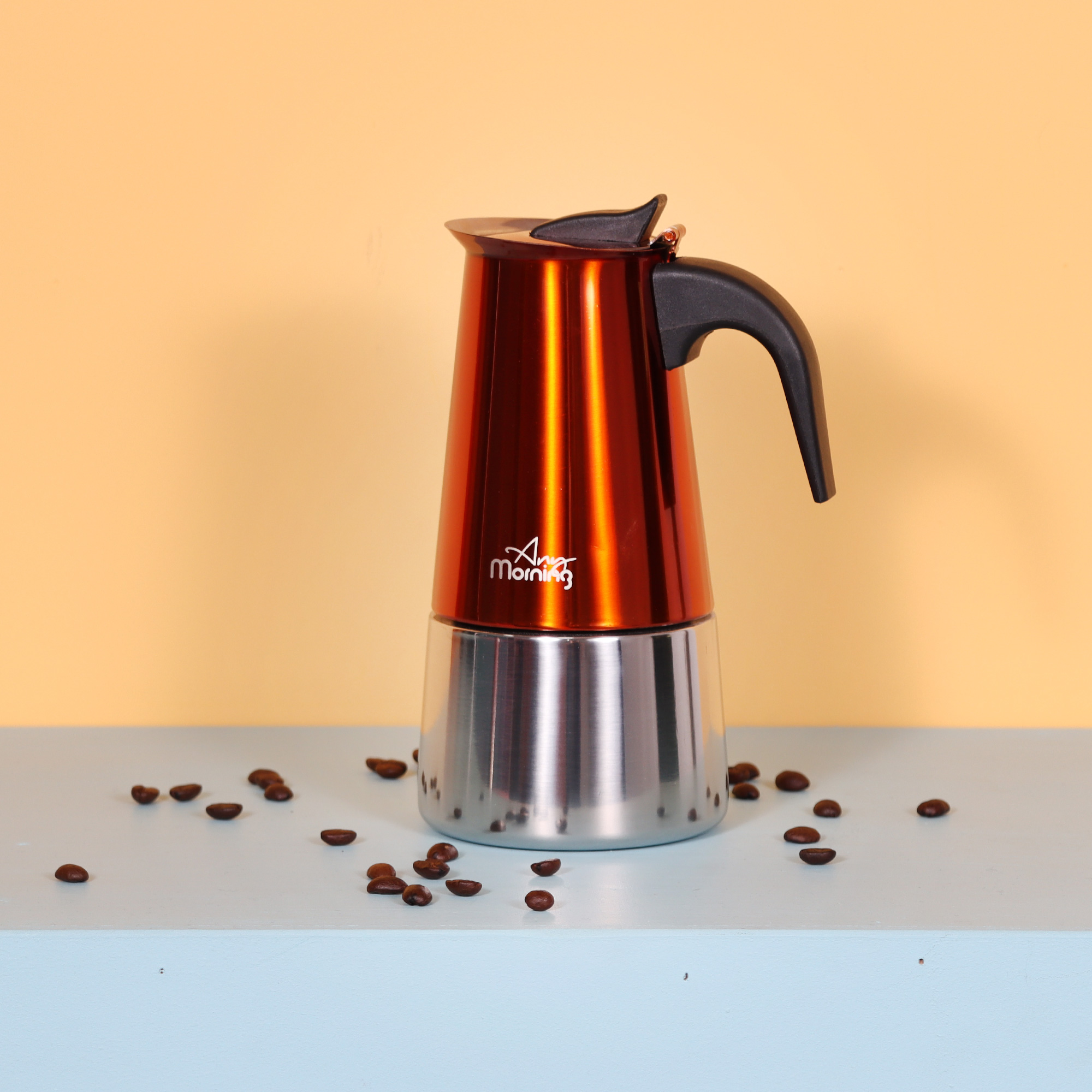 Parlak, turuncu espresso makinesi siyah saplı, açık mavi bir yüzey üzerinde.