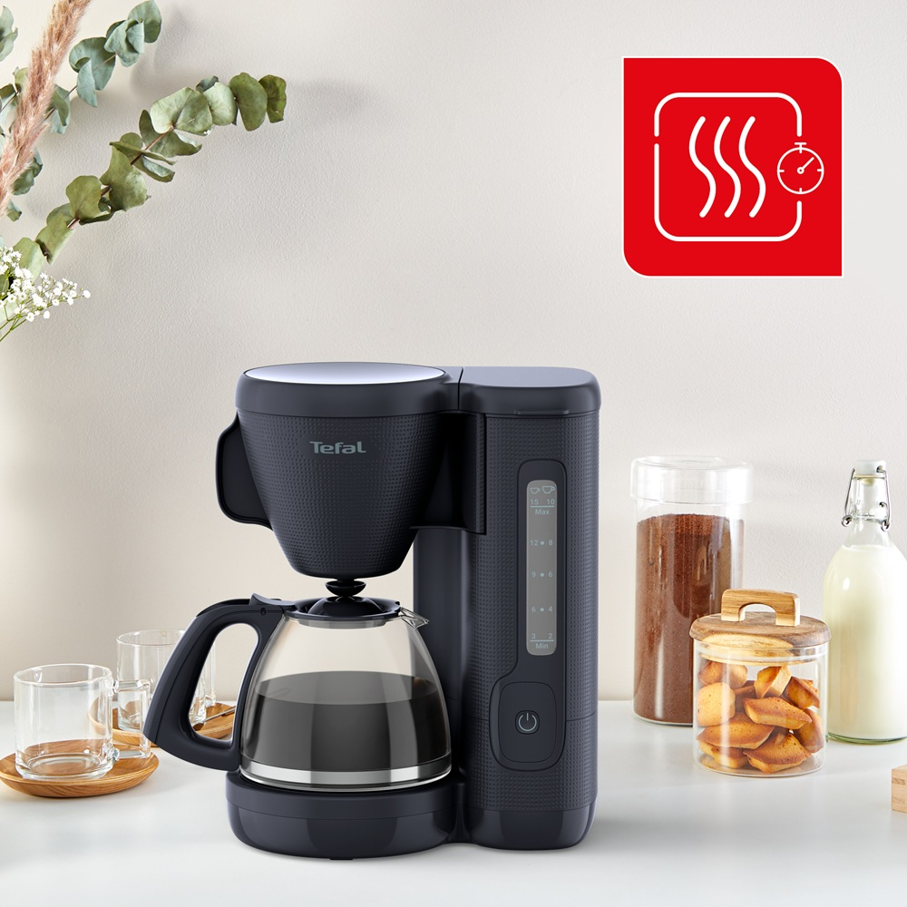 Siyah Tefal kahve makinesi, cam sürahi ile. Buhar ve zamanlayıcı içeren kırmızı kare simge. Kurabiye, kahve ve süt kavanozları.