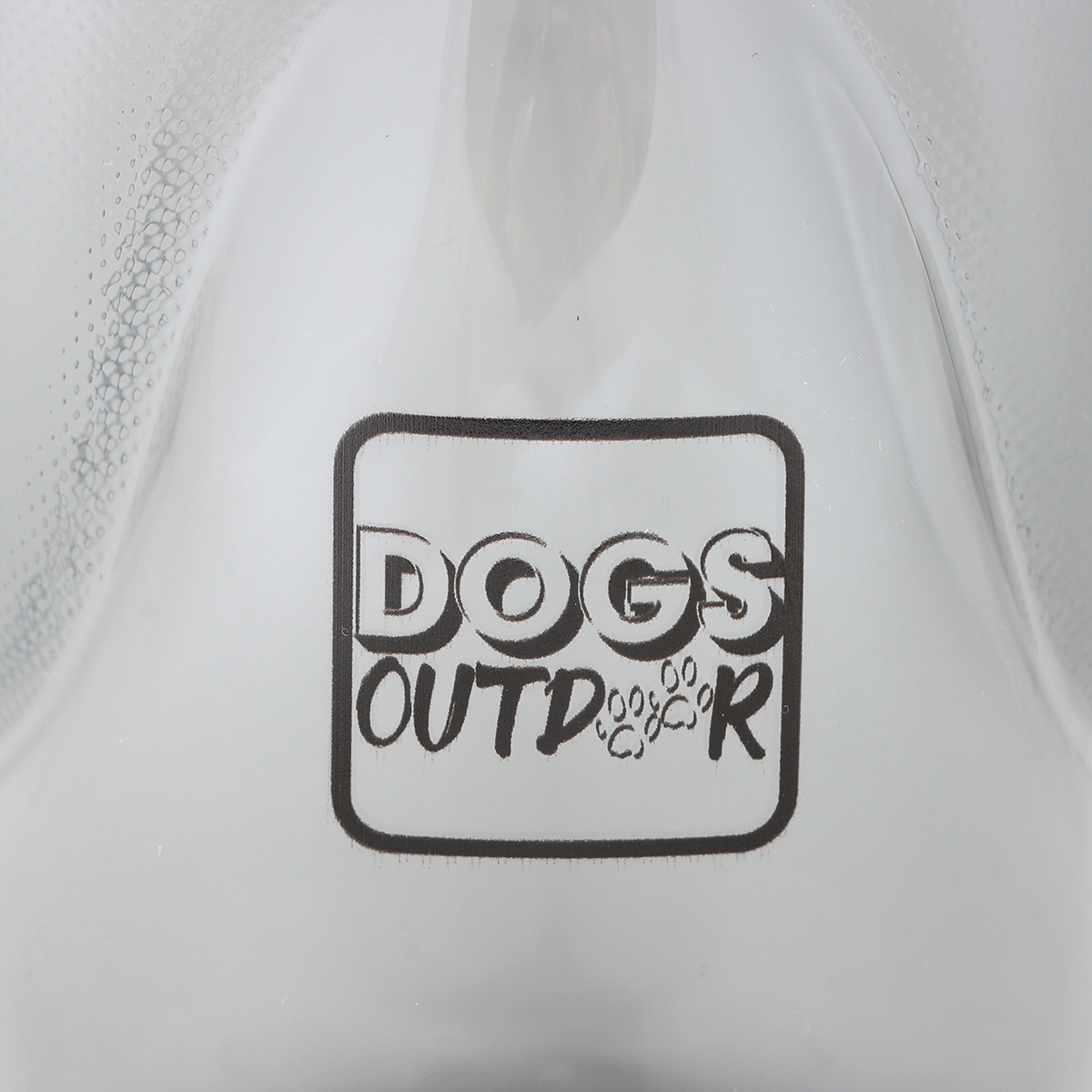 Siyah dikdörtgen bir çerçevede 'DOGS OUTDOOR' yazan ve pati izleri olan beyaz bir yüzeyin yakın çekimi. Arka plan beyazdır.