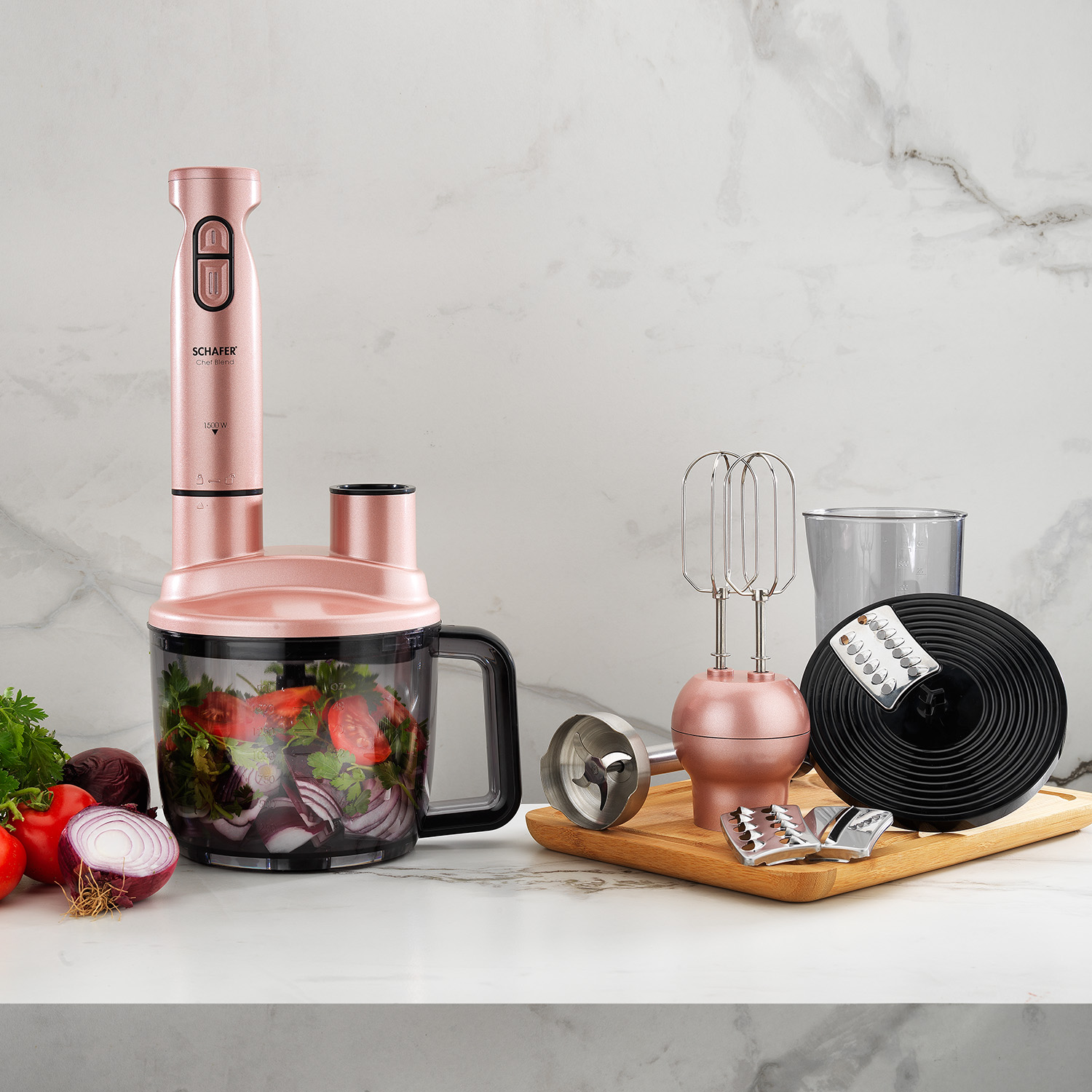Mermer bir yüzeyde aksesuarları ve sebzelerle birlikte pembe altın renginde bir mutfak robotu. Bir blender, mikser ve kesme bıçakları içerir.