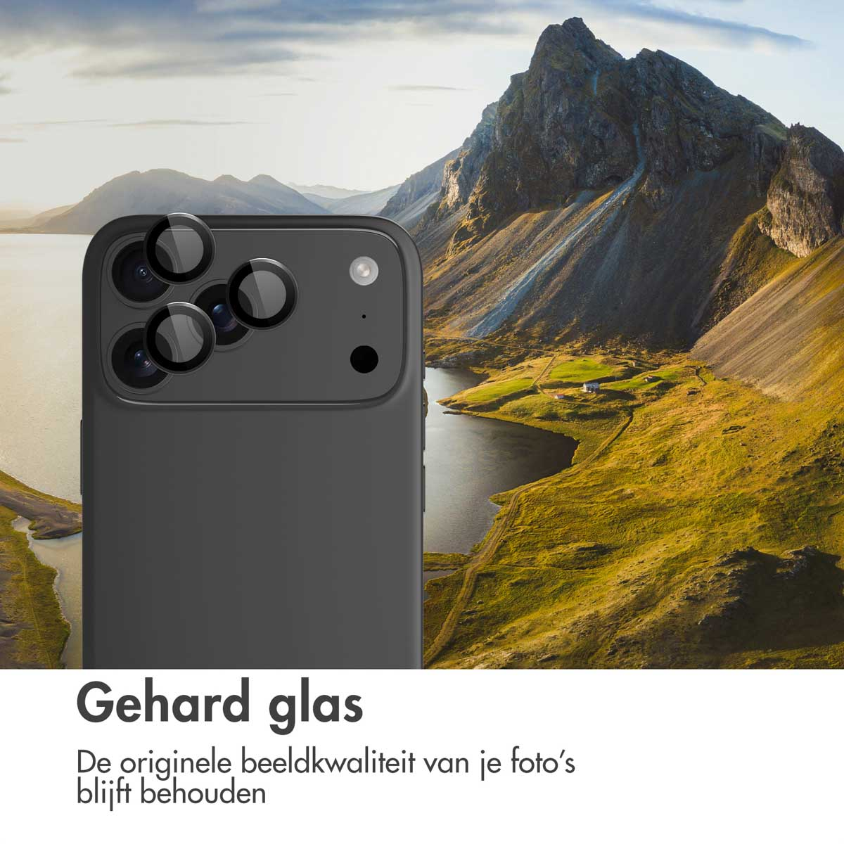 Een zwarte telefoon met lensbeschermers voor een berglandschap met een meer en groen gras.