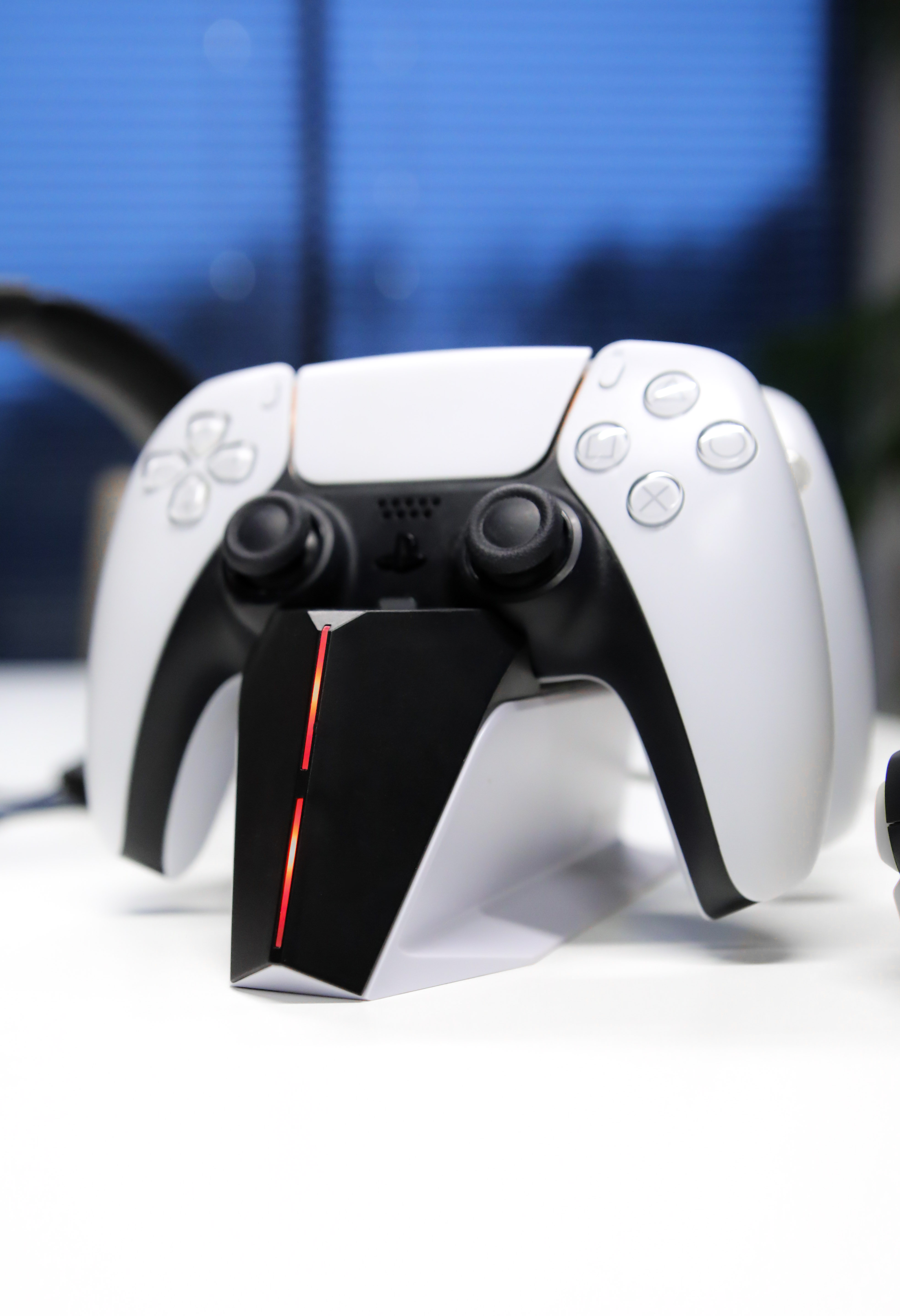 Biało-czarny kontroler do gier na białej powierzchni. Kontroler na czarnej podstawie z czerwonymi światłami.