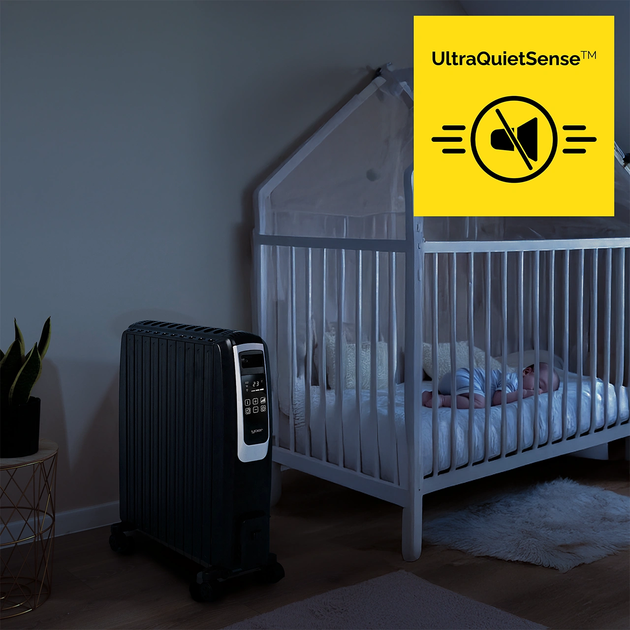 Czarny grzejnik olejowy stoi obok łóżeczka ze śpiącym dzieckiem. Żółty znak wskazuje 'UltraQuietSense'.