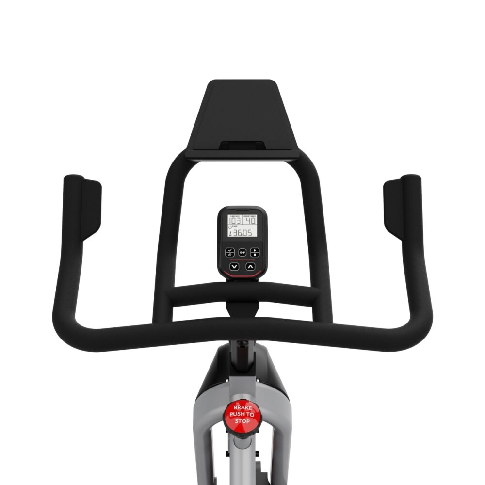 Vélo d'exercice. Guidon noir, écran affichant les statistiques et bouton de frein rouge. Le vélo est sur fond blanc.