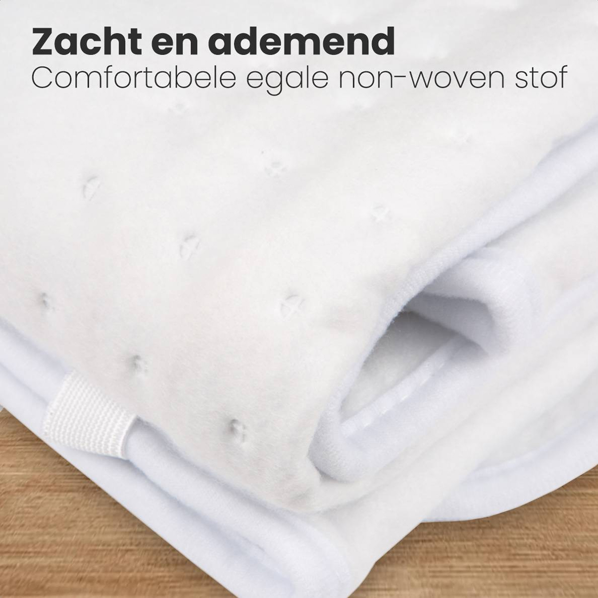 Gros plan sur un tissu blanc, doux et superposé. Le tissu comporte de petites indentations espacées uniformément. Une sangle blanche est visible.