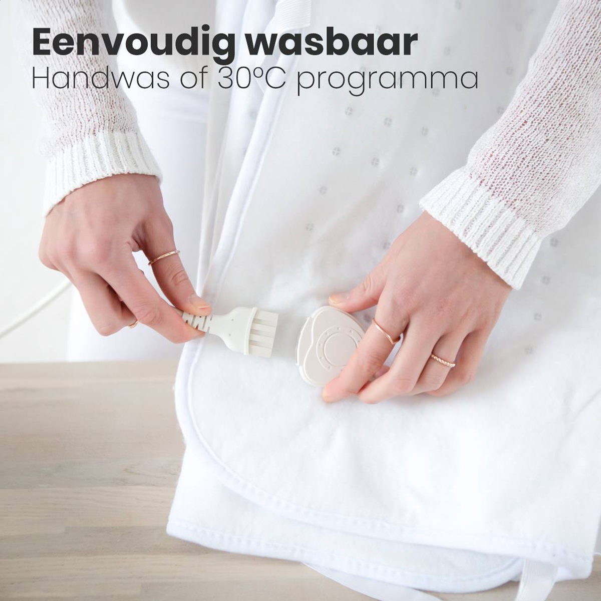 Les mains connectent une prise blanche à un appareil blanc sur une couverture blanche. Texte : 'Facilement lavable. Lavage à la main ou 30°C'.