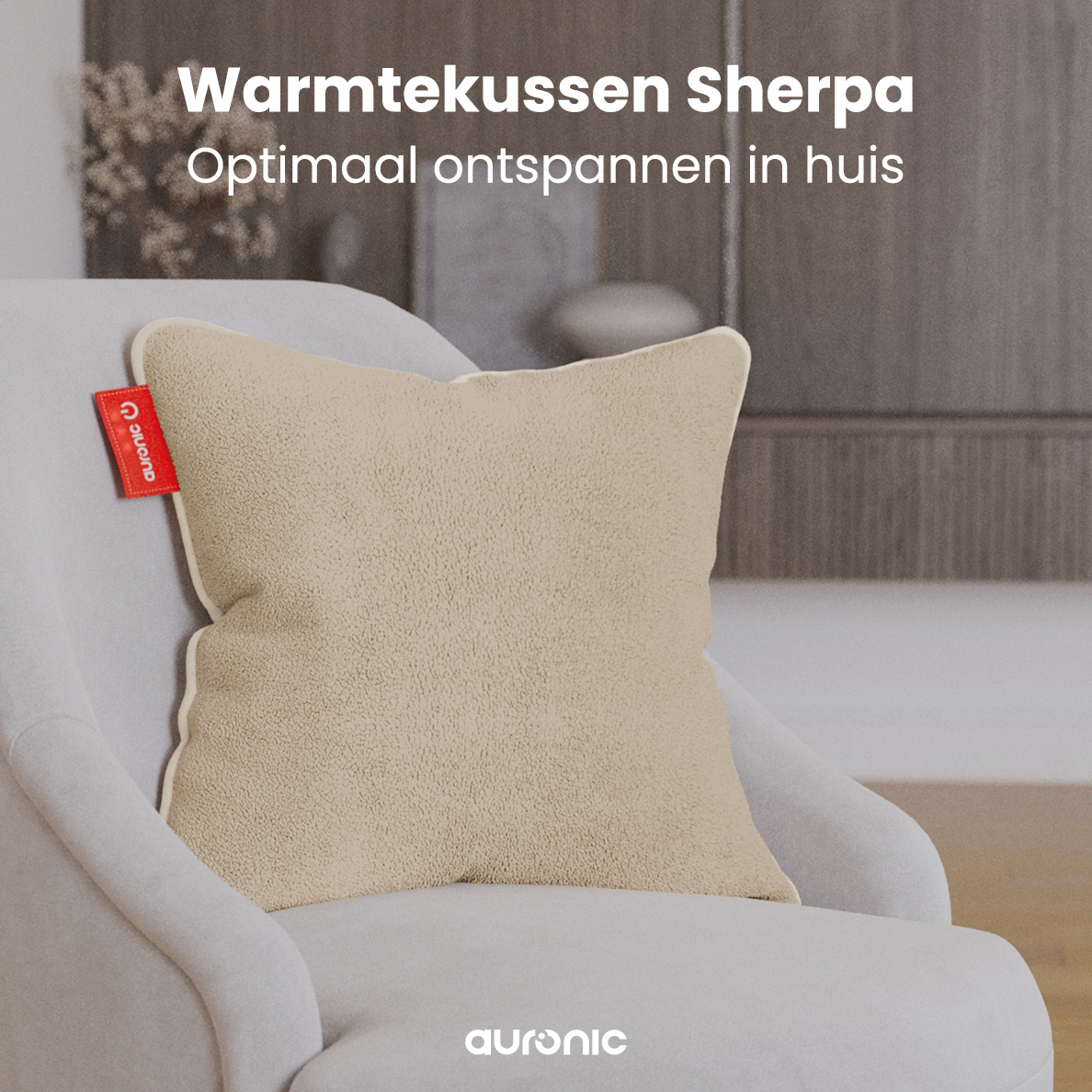 A beige Sherpa cushion on a white chair. A red tag with 'auronic' is on the cushion. Text: Warmtekussen Sherpa, optimaal ontspannen in huis.