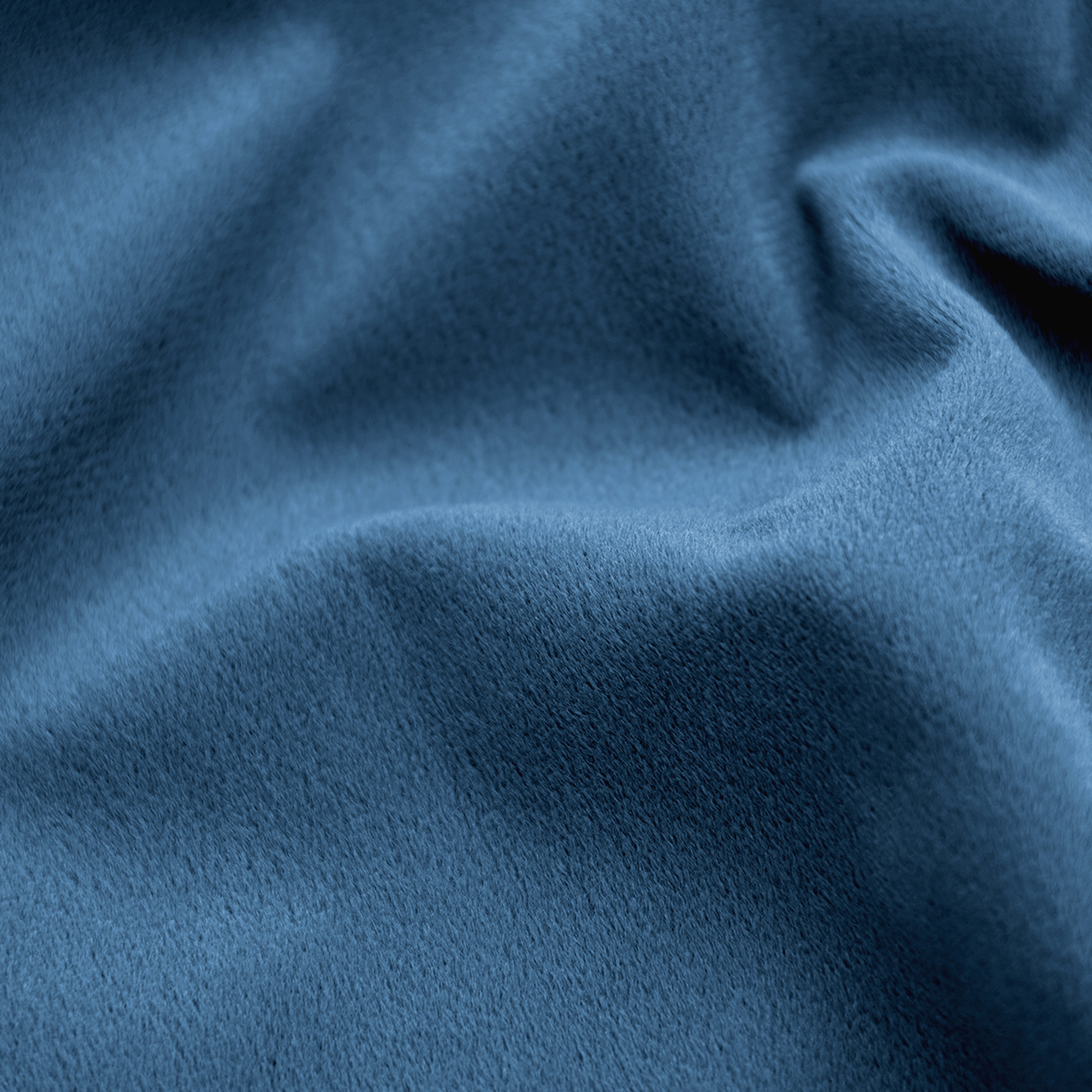 Close-up van een blauwe stof met zachte textuur en zichtbare plooien, waardoor schaduwen ontstaan.