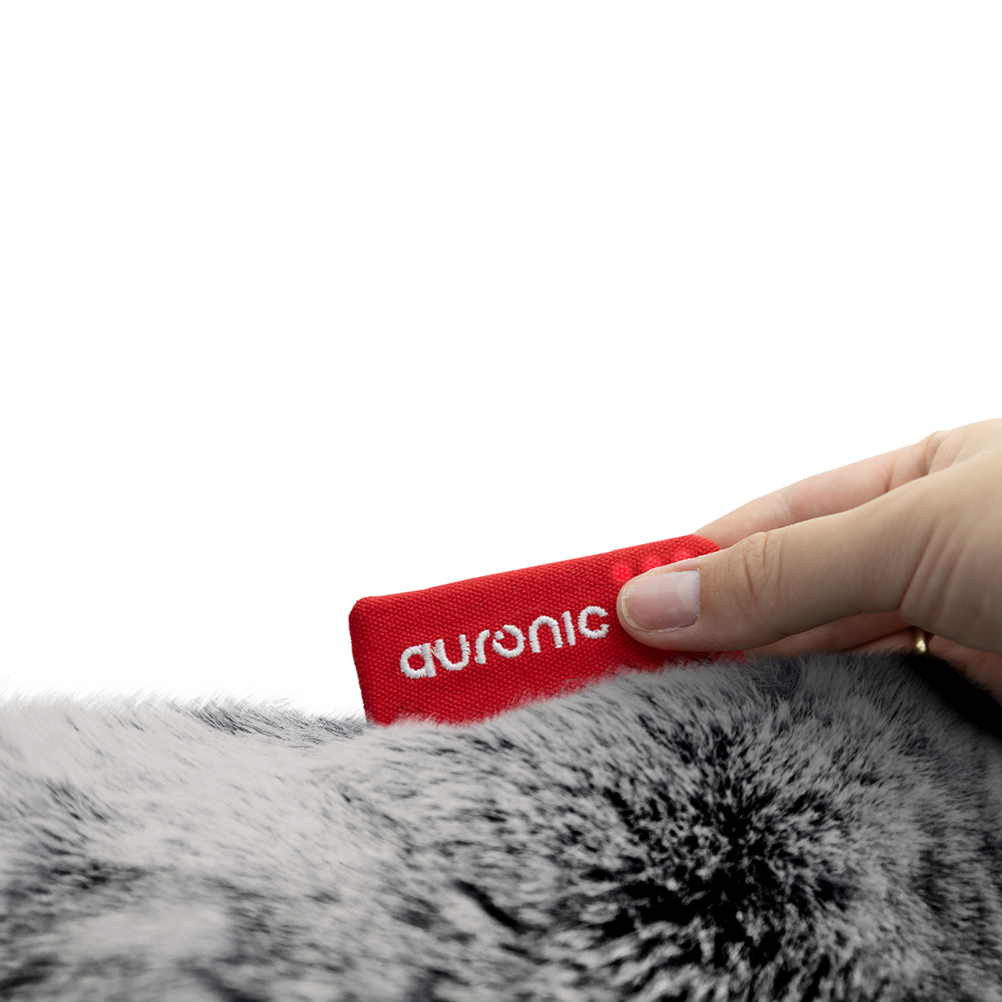 A hand holds a red tag with 'auronic' on it, placed on a gray fur background. White background.