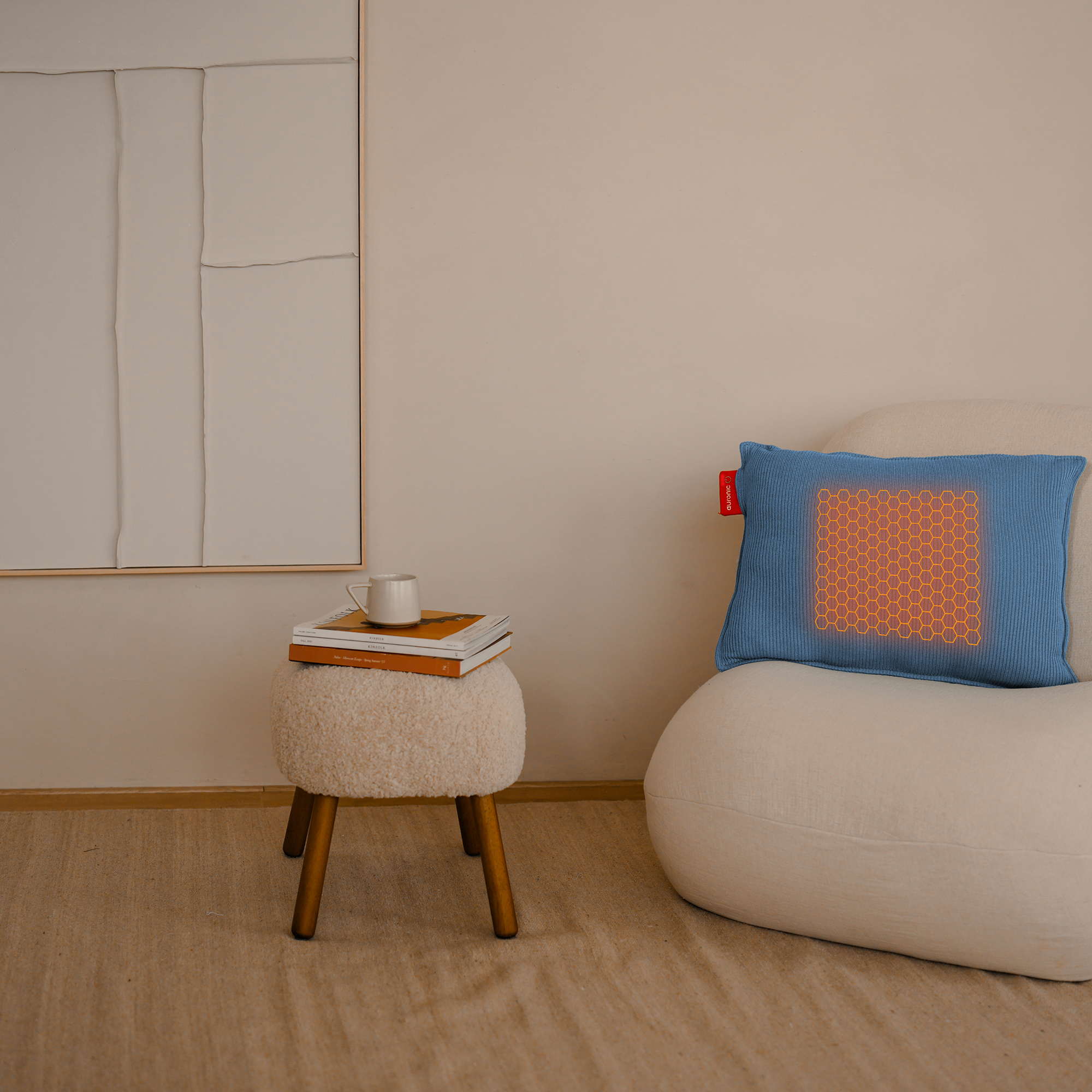 Een kamer met een stoel en een kleine tafel. Een blauw kussen met een oranje patroon. Een kopje koffie op tafel.
