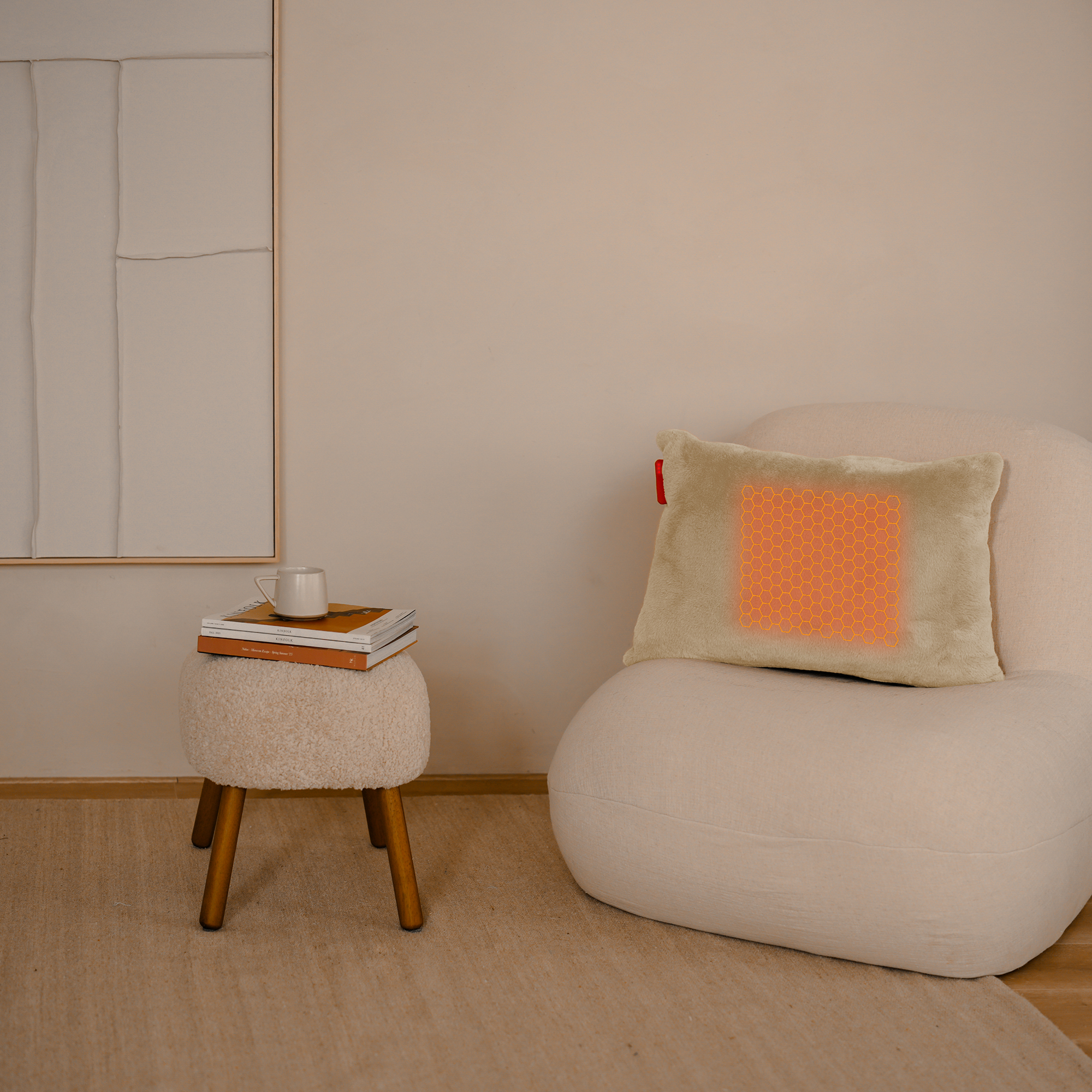 Een gezellig interieur met een stoel met kussen, een tafeltje met boeken en een mok, en een beige muur.