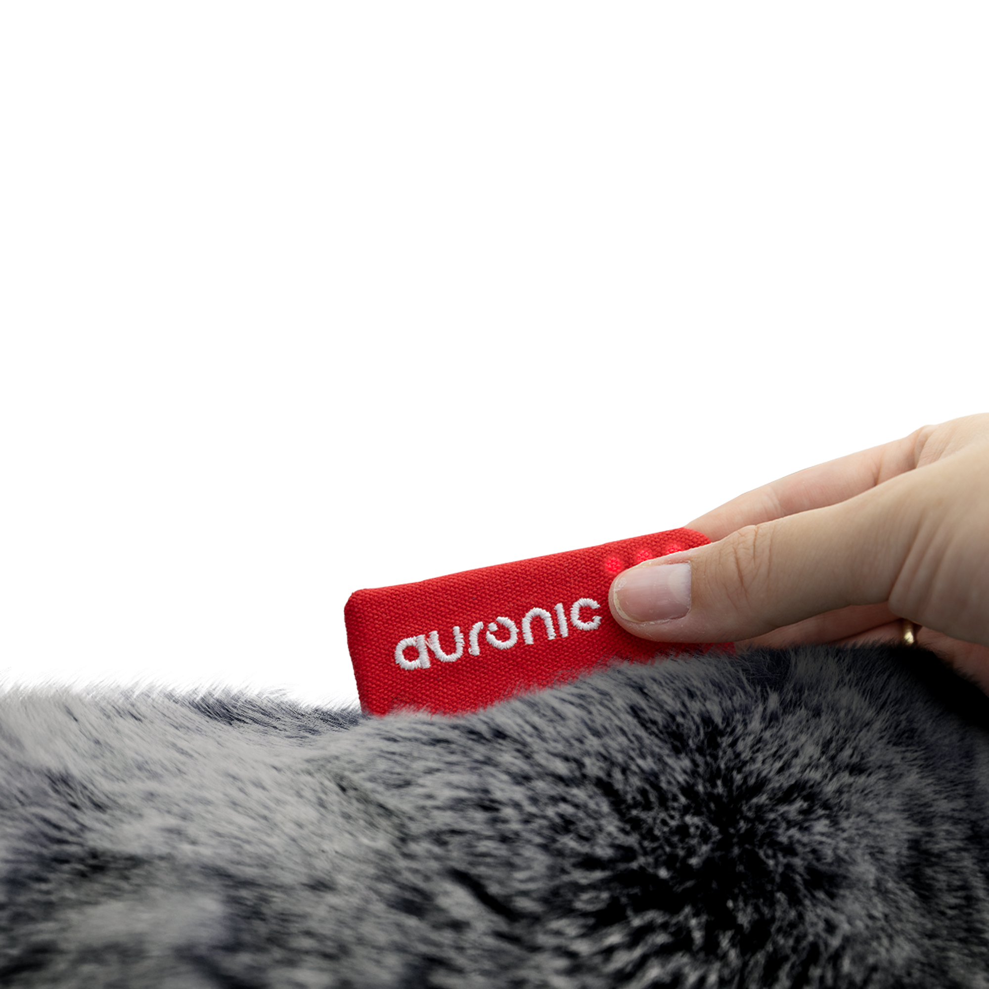 Une main tenant une étiquette rouge avec le mot blanc 'auronic', placée sur une surface grise et moelleuse.