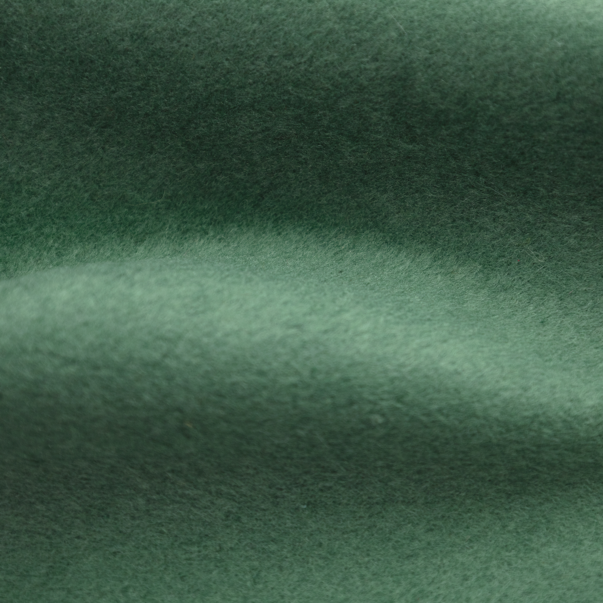 Gros plan d'un tissu vert foncé texturé, avec de subtiles variations de lumière et un aspect doux et flou.